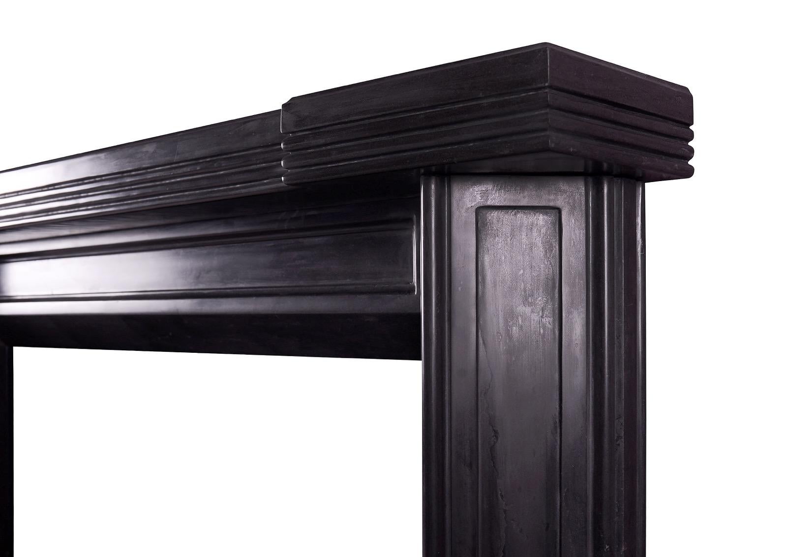 An unusual Art Deco style fireplace in black marble. The triangular, panelled jambs surmounted by panelled frieze and reeded shelf. A copy of an early 20th century original. A clean design in a marble would suit the Classic or the