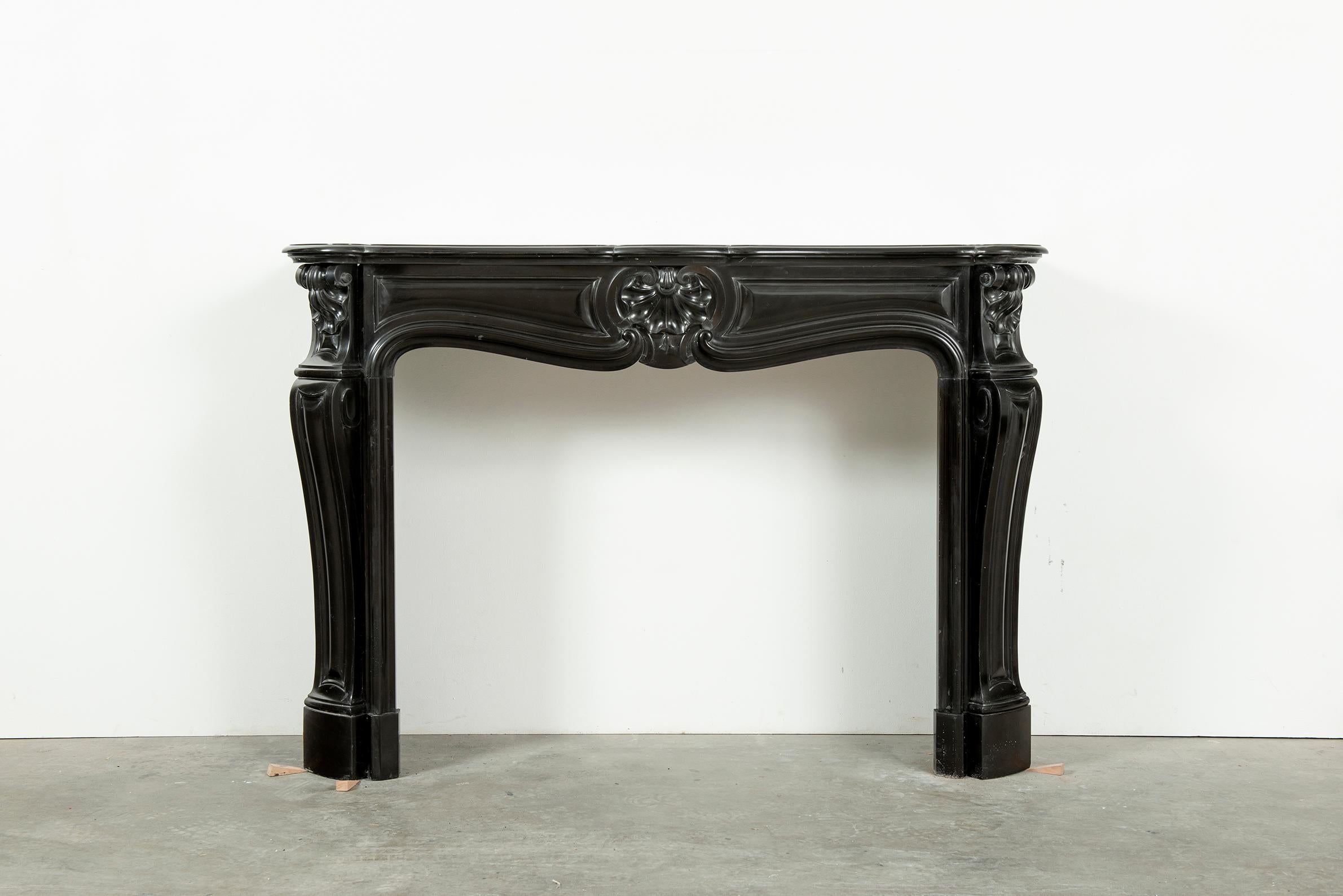 Black Marble Louis XV Fireplace Mantel, 19th Century

Beautiful decorative piece, nice proportioned with serpentine breakfront shelf above a fielded freeze centered by a lovely central scallop echoed in the beautiful endblocks which sit above