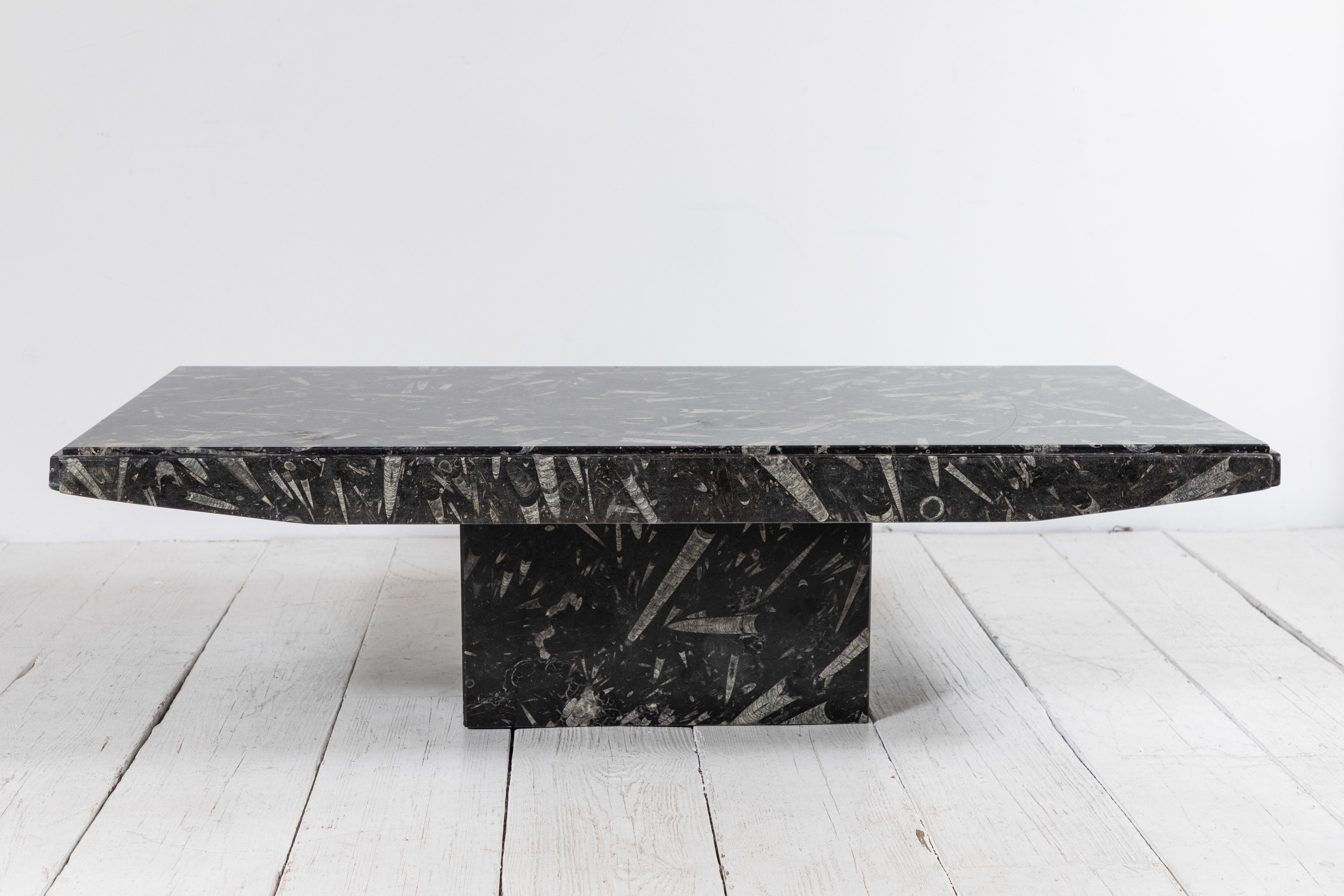 Angular modern black marble coffee table with chunky center support.