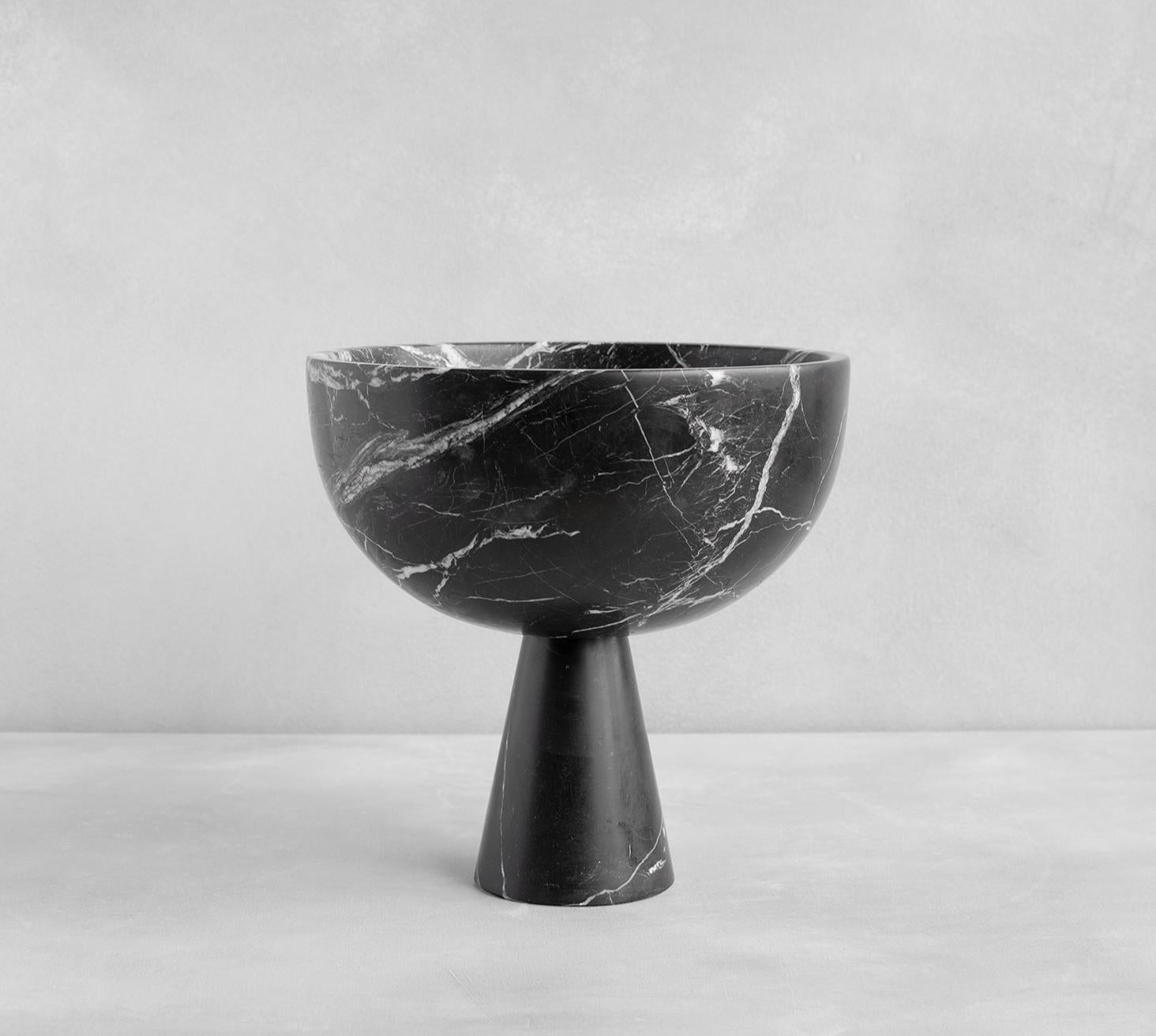 A substantial black marble bowl with unique white veining rests atop a pedestal for a grand presentation of fruits and vegetables. 

Exposure to the acid of citrus fruits can stain marble. Due to the natural properties of marble the colour and