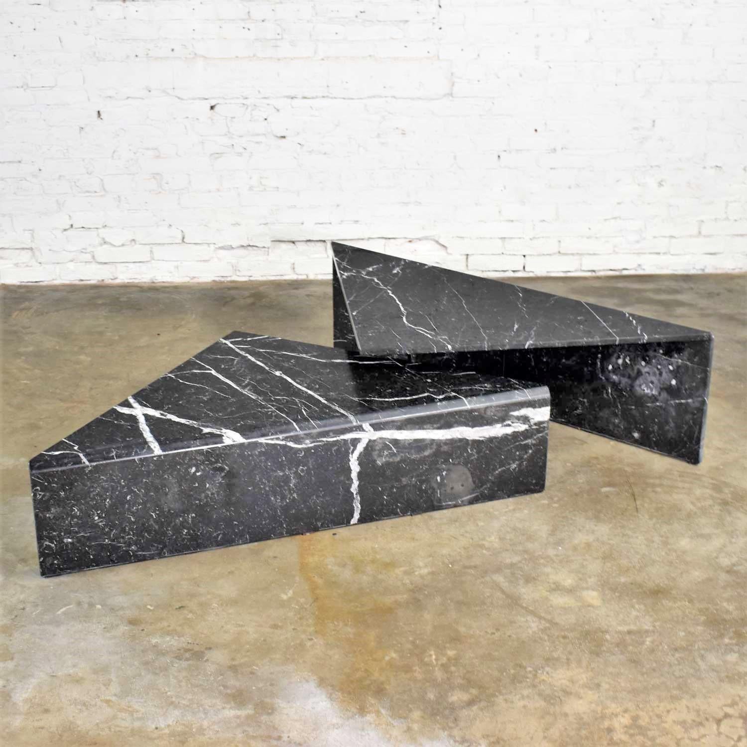 Handsome pair of bi-level black marble triangle tables to be used together as a coffee table or separated as end tables. They are in the style of Up & Up, Italy. One is in excellent condition the other is in wonderful condition but with a repair to