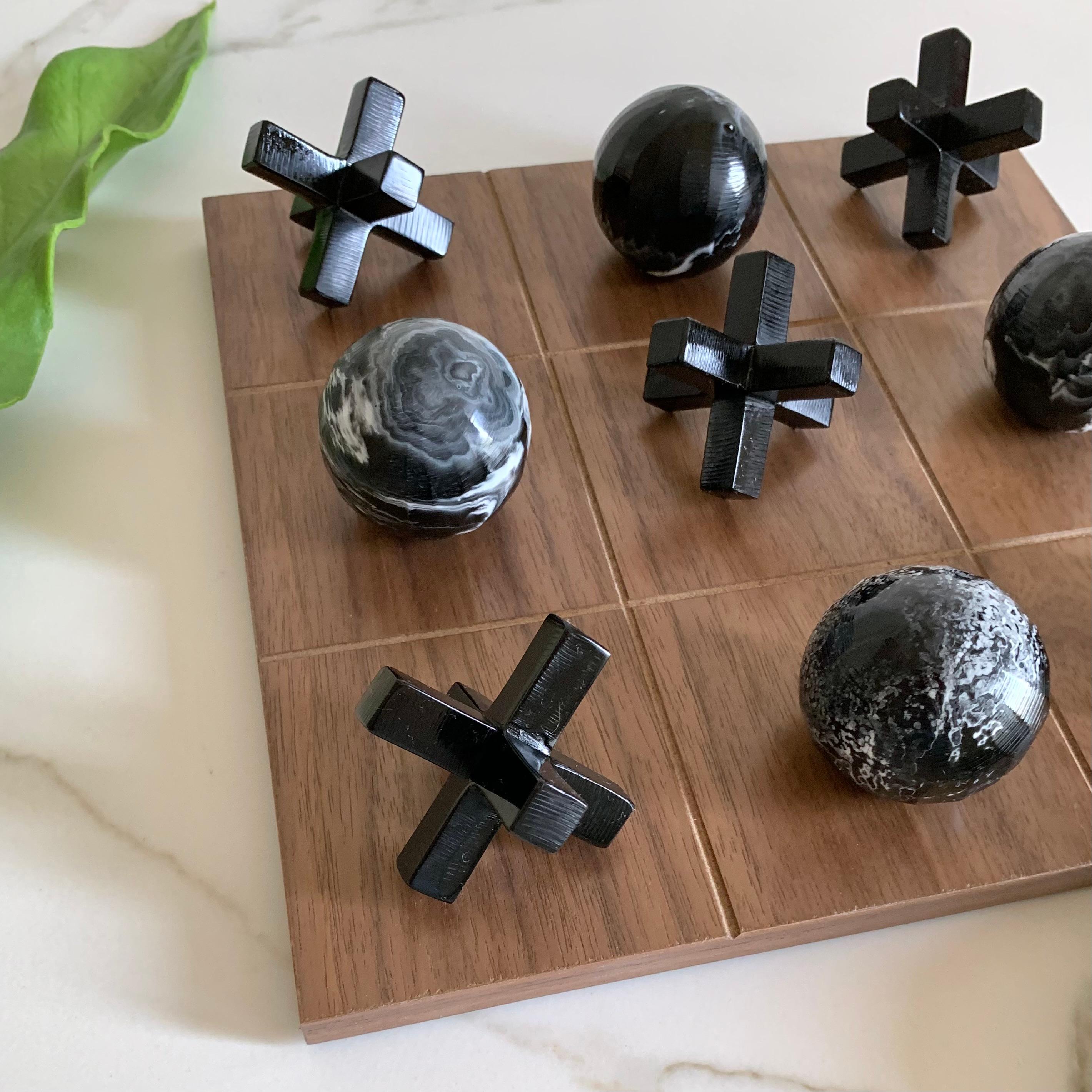 Notre Tic Tac Toe est une version magnifique, moderne et amusante du jeu classique. Les pièces tridimensionnelles sont fabriquées à la main en résine noire avec une texture marbrée blanche et le panneau est en placage de bois de chêne. Ce sera la