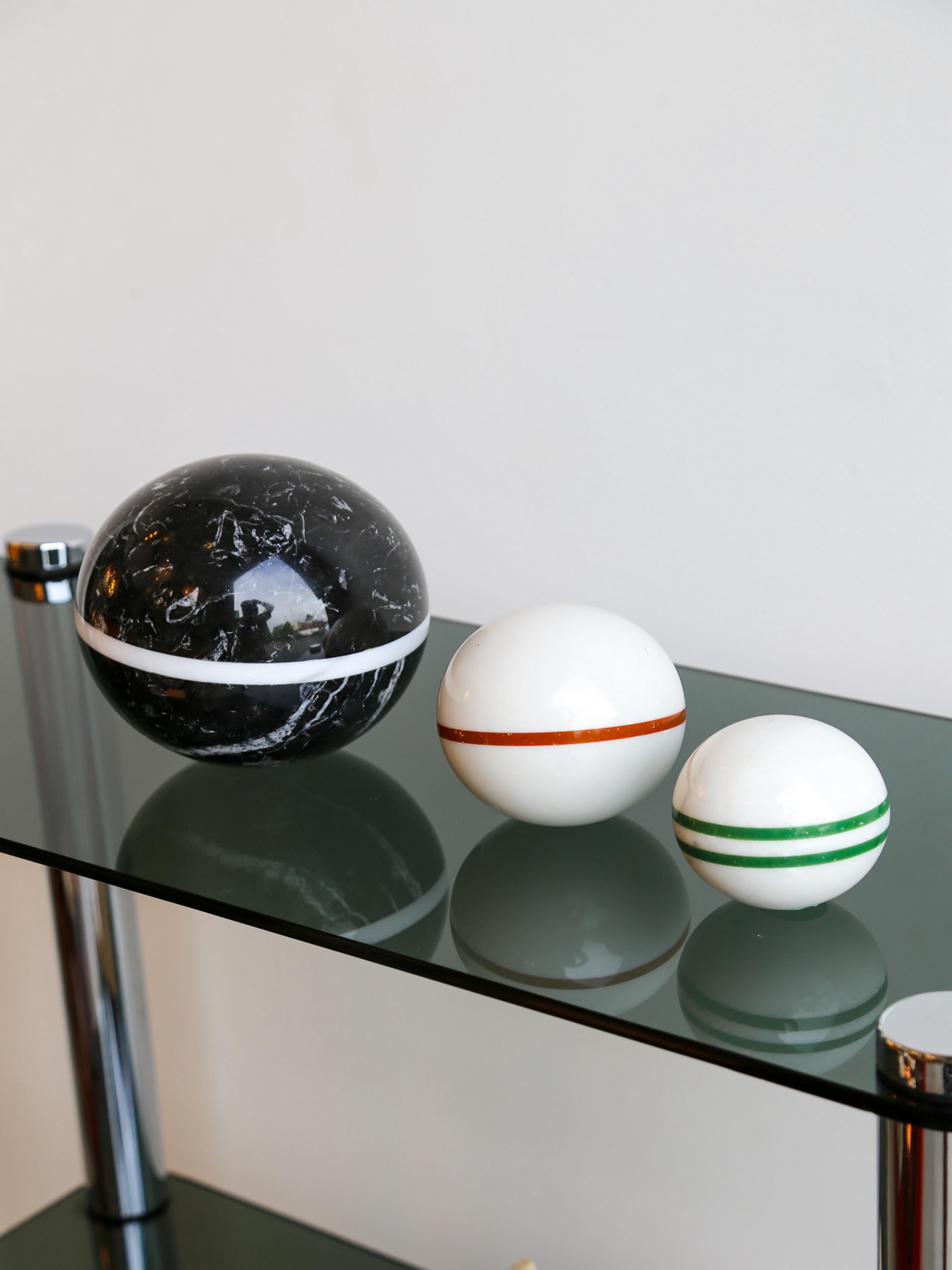 A sculptural sphere of bold contrast and minimalist precision, hand-carved in Italy in the 1980s. Crafted from rich Nero Marquina marble, its deep black surface is naturally veined with white fossils and crystalline streaks, intersected by a precise