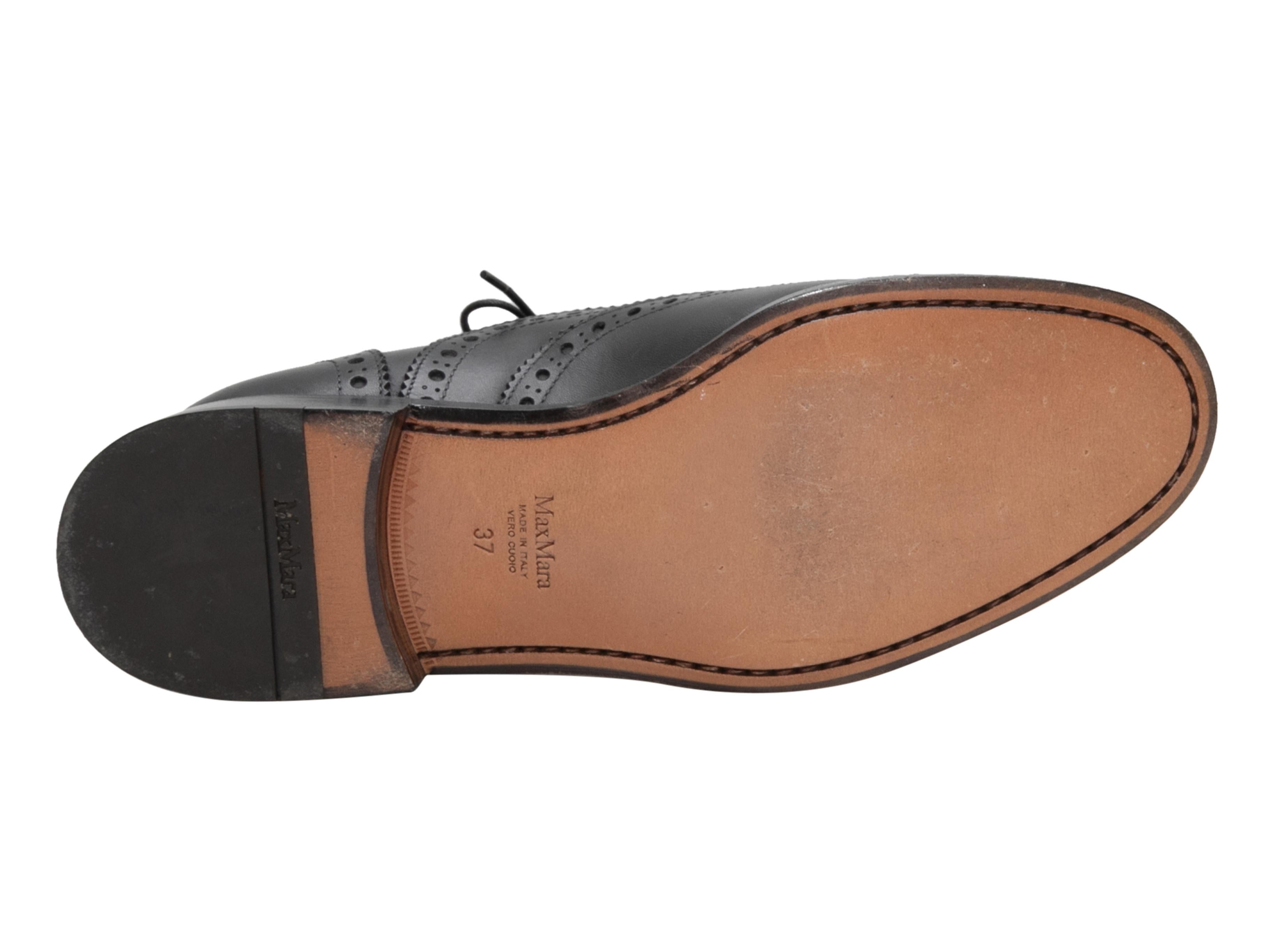 Black leather brogue oxfords by Max Mara. Stacked heels. Lace-up tie closures at tops. 1