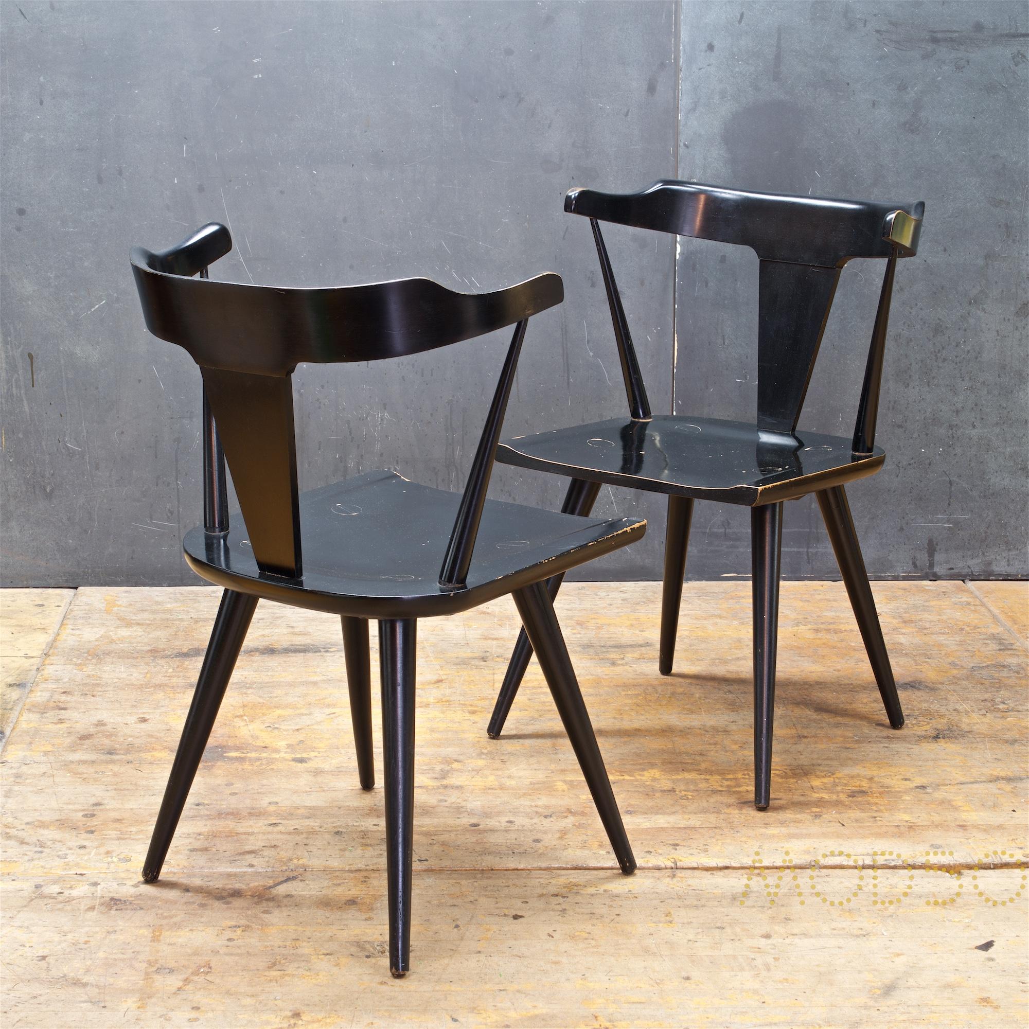 A pair of Paul McCobb Planner Group dining armchairs model Nº1530 in original black enamel finish with labels to verso of each chair. Lots of paint loss in the seat areas, otherwise tight and usable.
