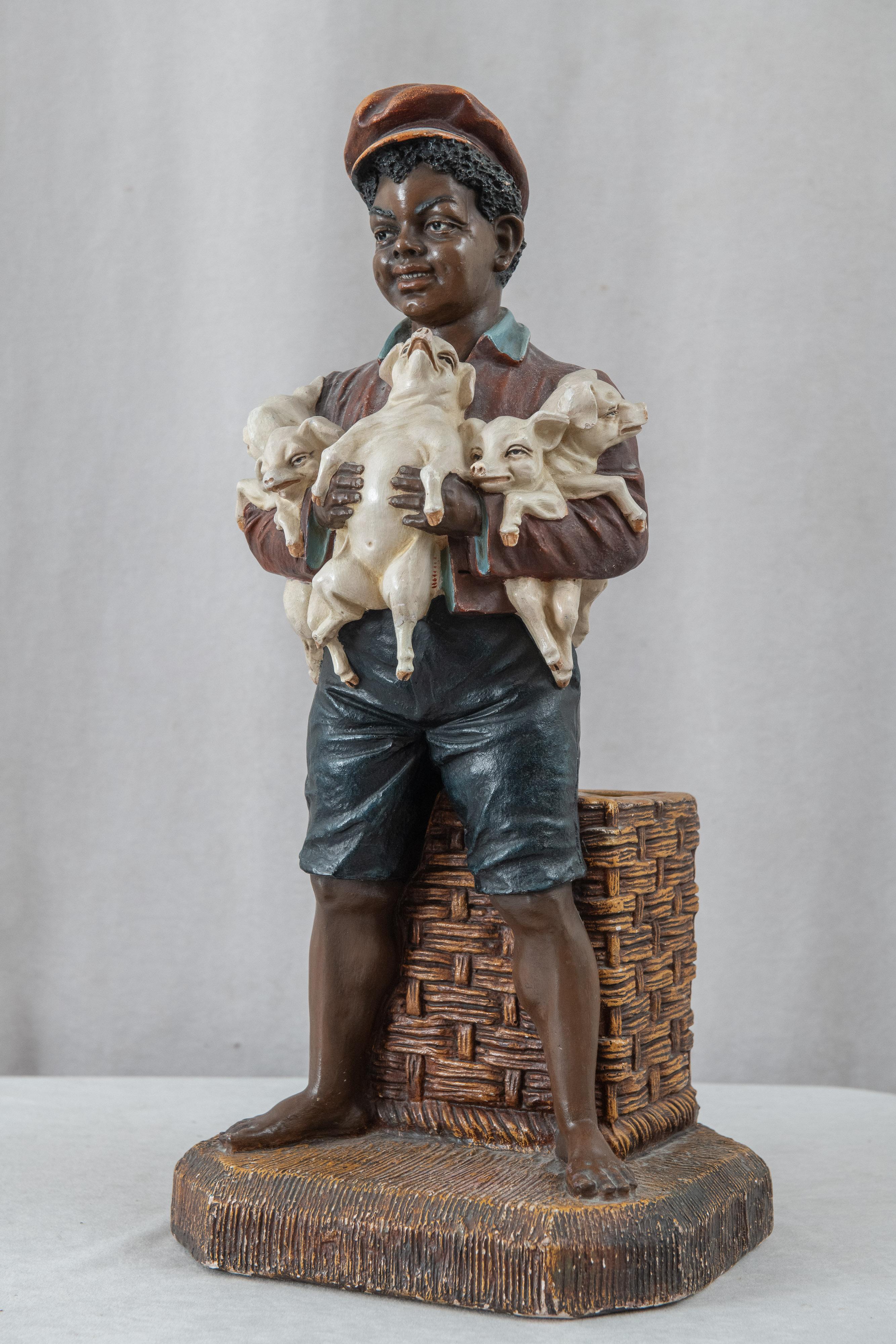  This highly amusing and beautiful sculpture of a young black boy holding 4 baby pigs should bring a smile to anyone's face. Richly painted and detailed casting make it very realistic. There is an area in the back for storage of small items,