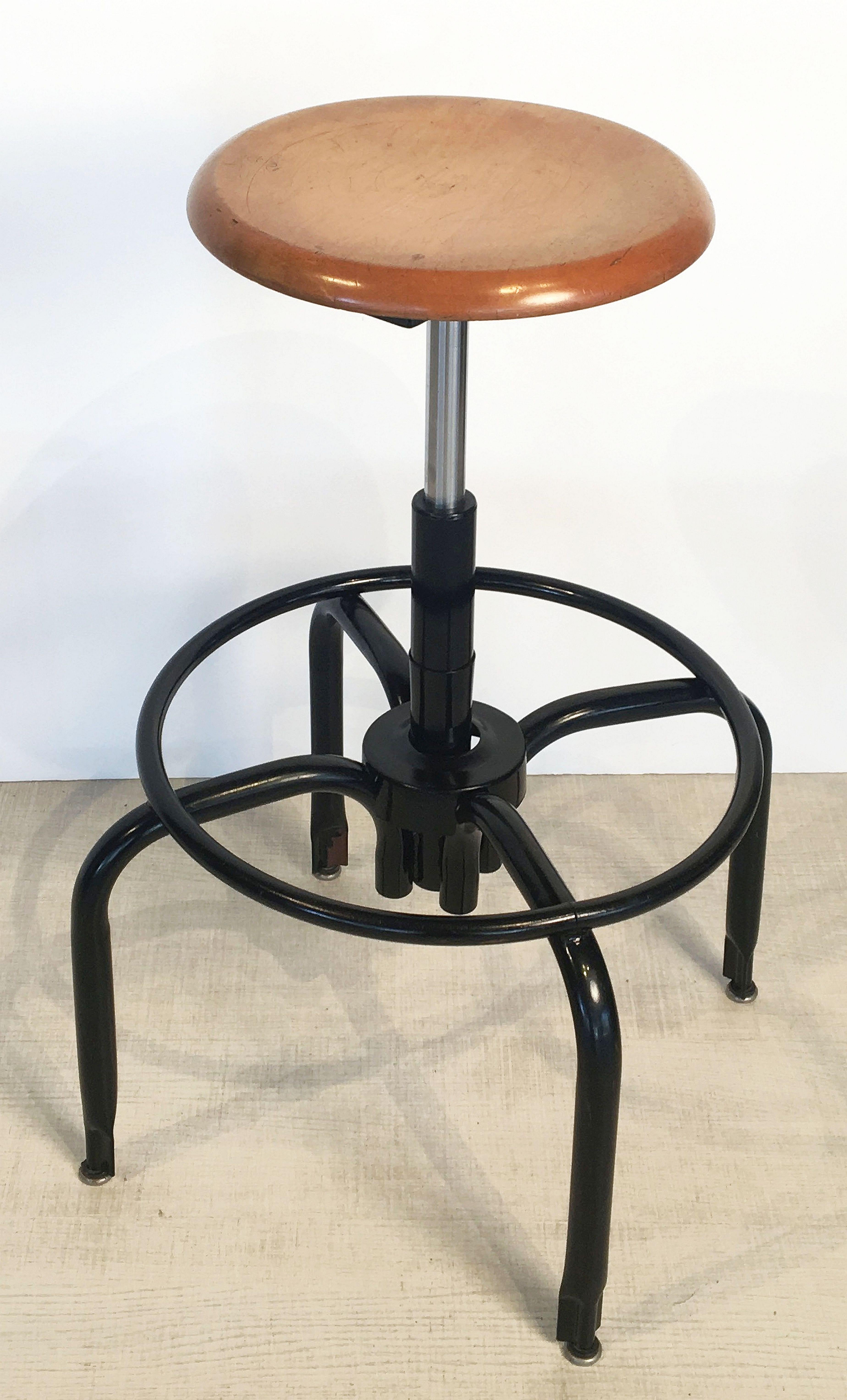 Un set di cinque sgabelli da bar americani vintage in metallo tubolare nero e cromato, ogni sgabello con sedile rotondo girevole in legno, appoggiato su un supporto a quattro gambe, con poggiapiedi circolare.

Cinque disponibili - Prezzo