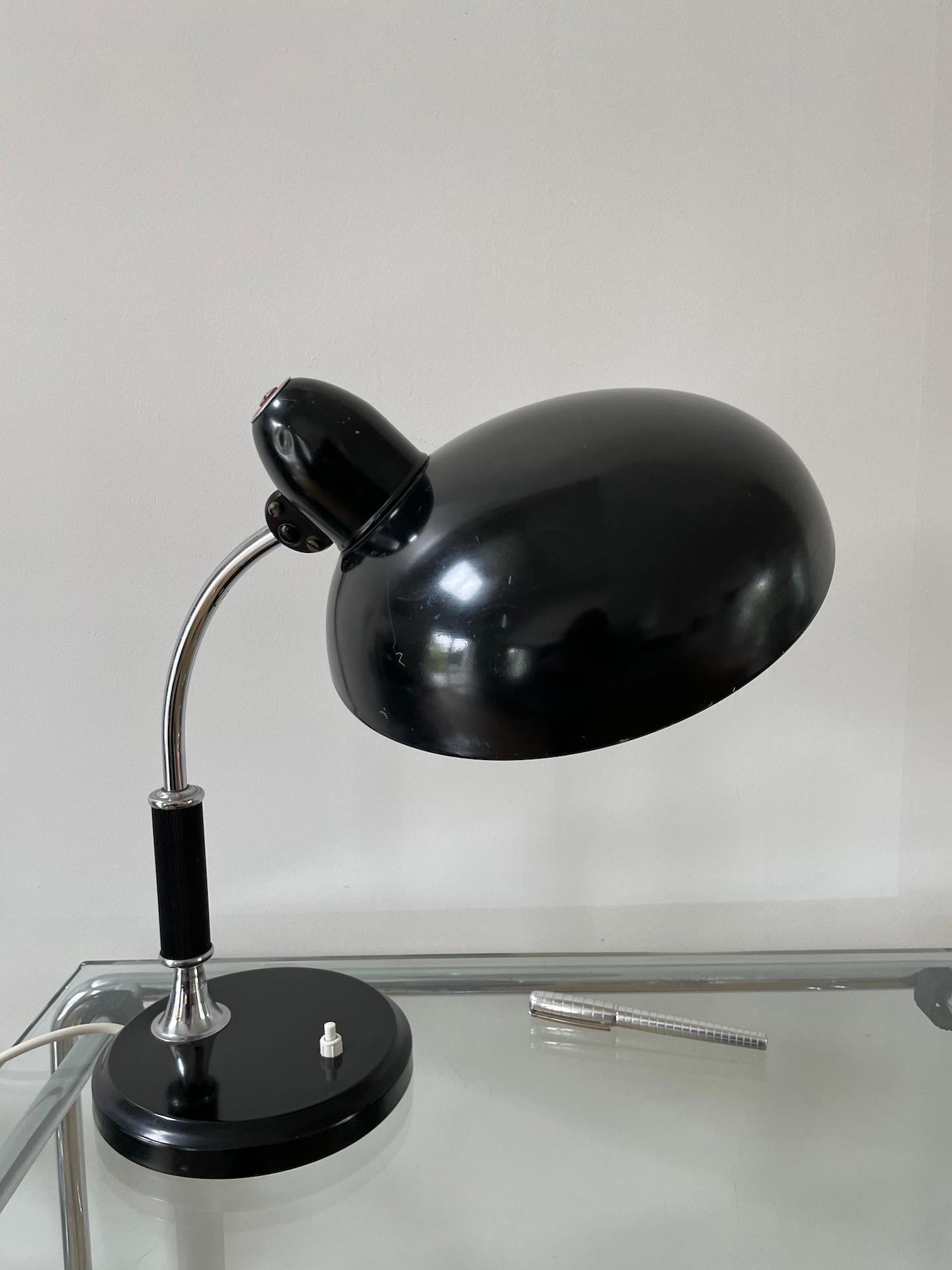 Black metal and chromed table light by Helo Leuchten, circa 1945.

With a sleek design reminding the Bauhaus period this table lamp is modern and functional. The shade is articulated enabling to swivel it frontwards, backwards and sideways.

The