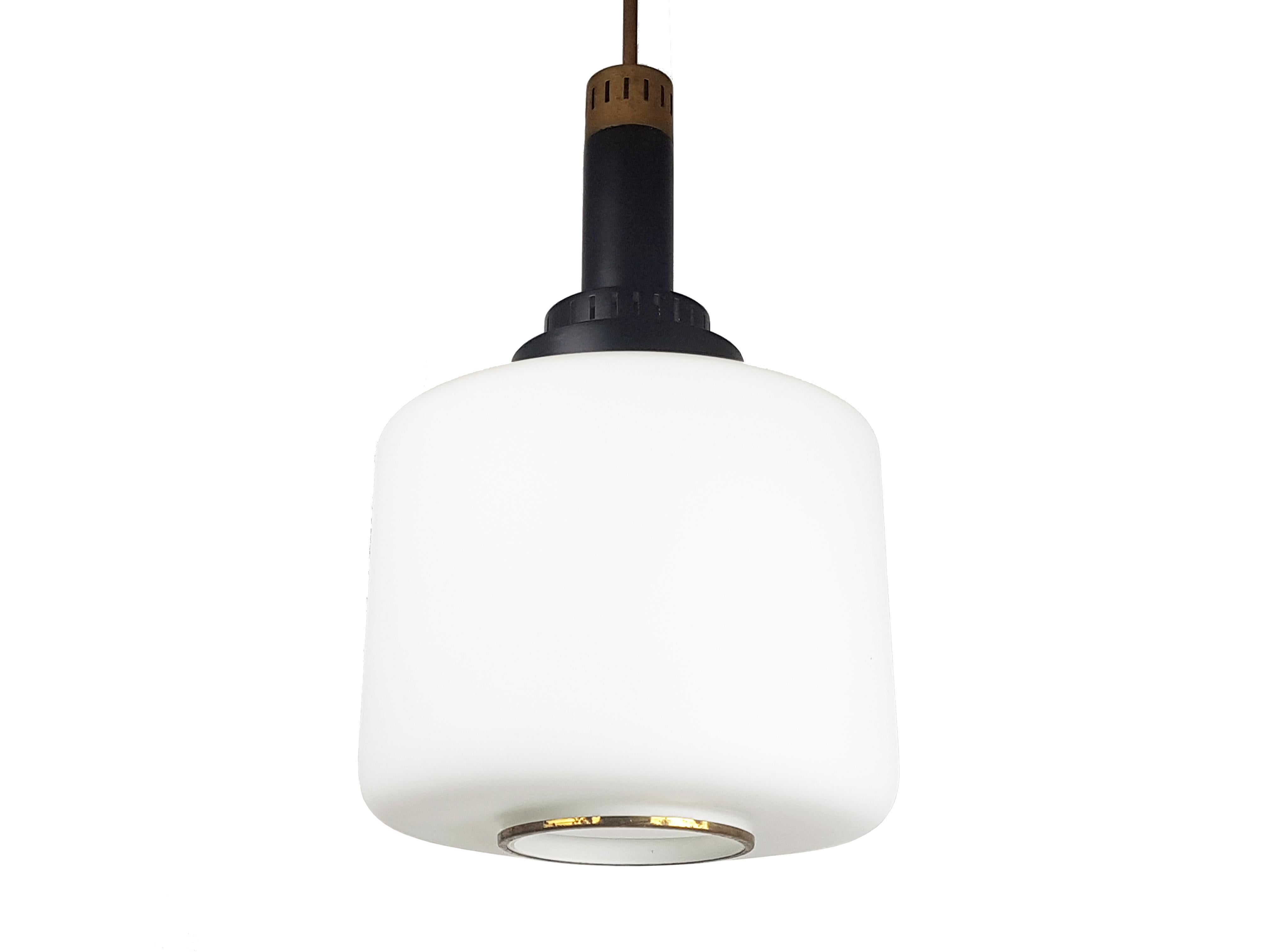 This pendant was produced in Italy between the '50s and the '60s.
It was made by a black painted aluminum body with brass rod and details and a sandblasted cylindrical glass shade.