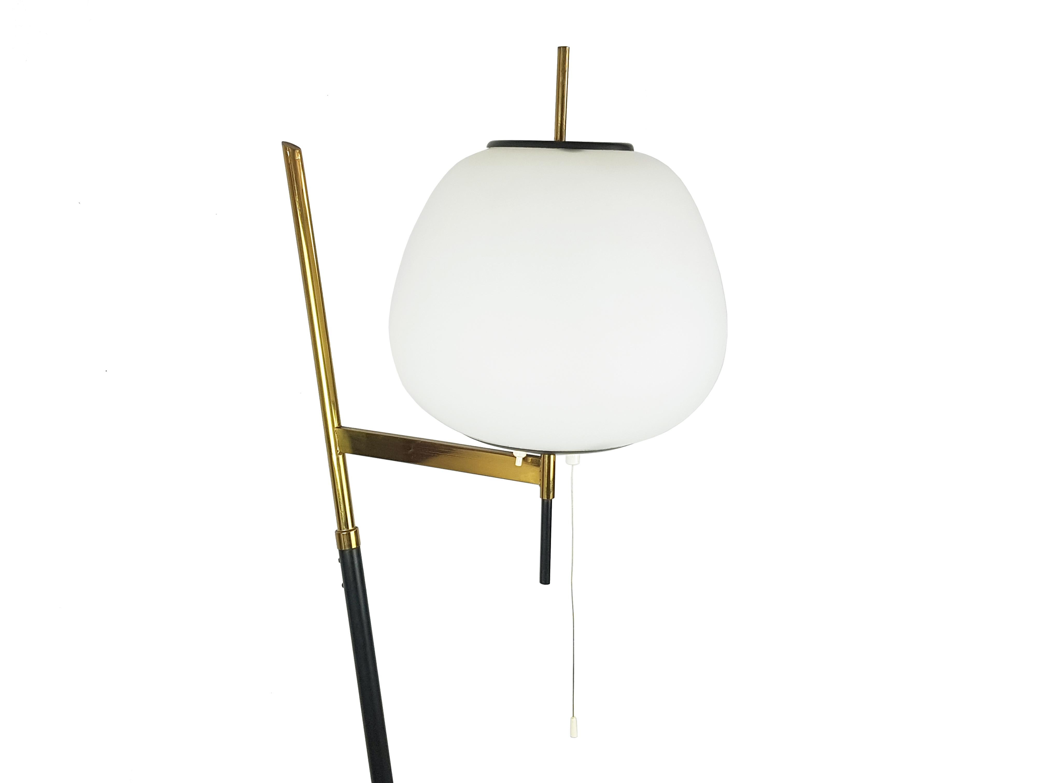 Black metal and brass structure with white opaline glass shade. Particular 1950s floor lamp with inclined structure and refined brass details. 

The floor lamp is equipped with 2 different light sources: the one with the cord and  E27 (large socket)
