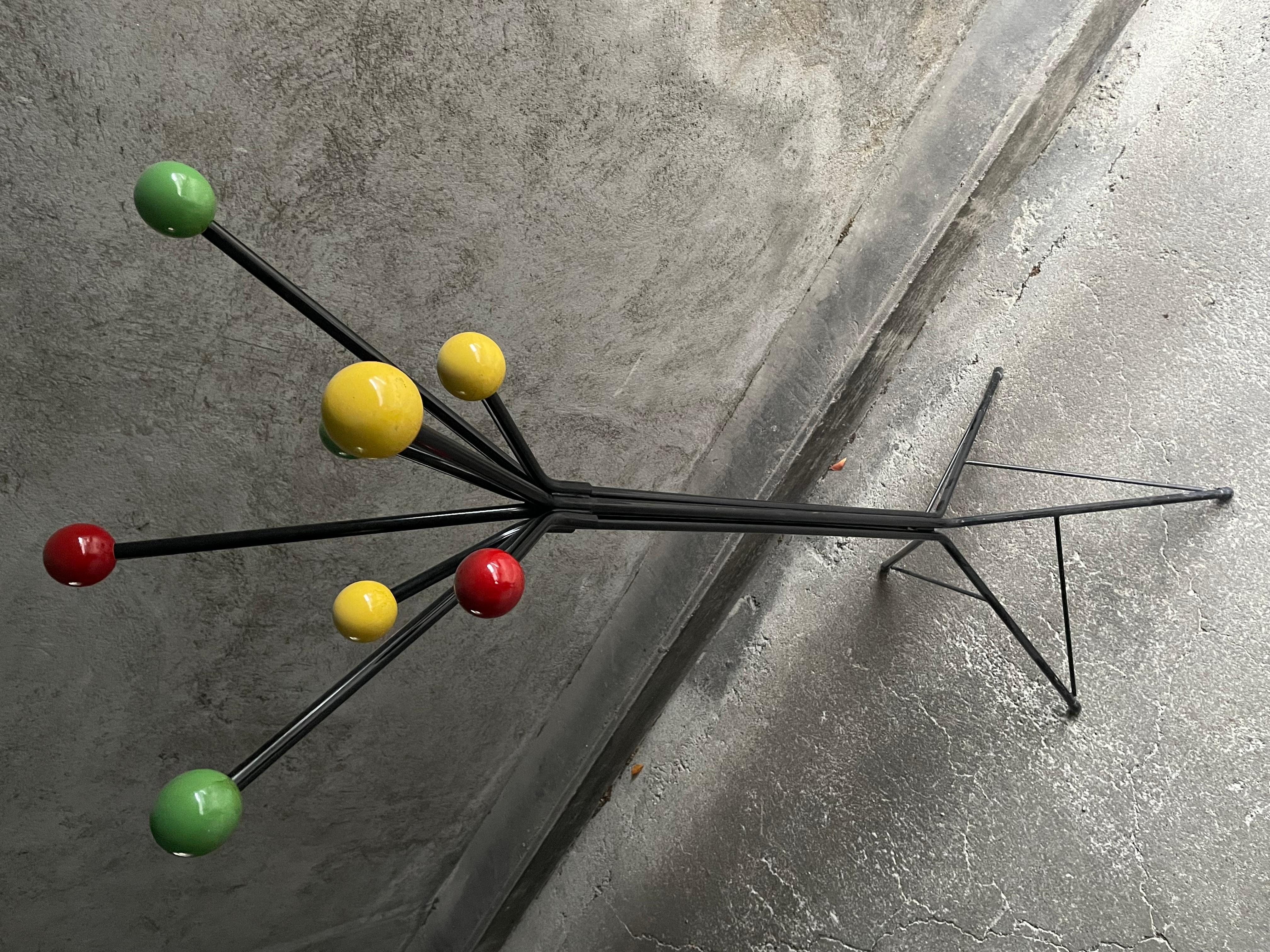 Coat rack on legs in the style of Roger Feraud. Black tubular metal structure and 8 polychrome balls for hanging coats, hats or umbrellas. Good general used condition. Dimensions: l50 x d50 x h170 cm.