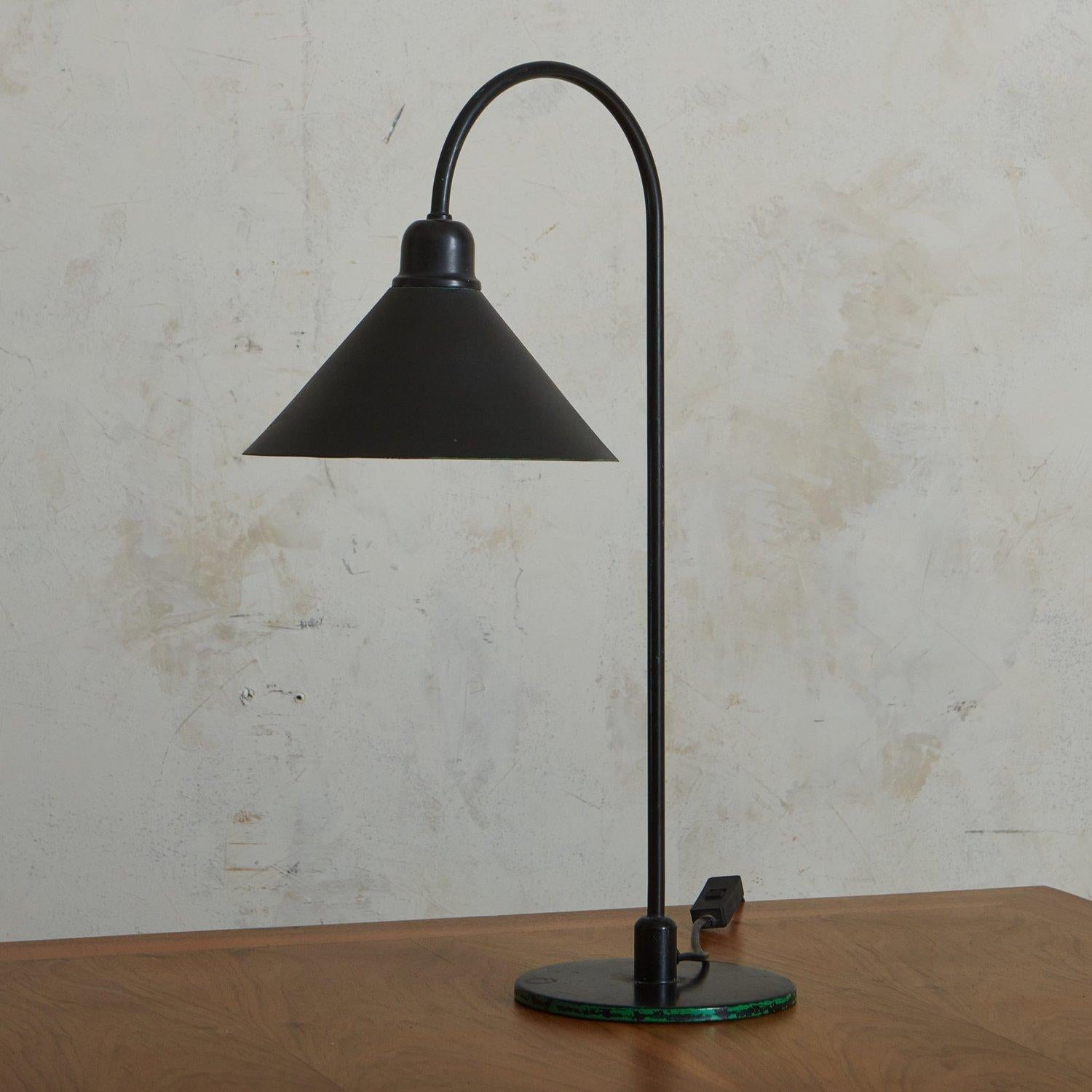A vintage French black metal desk lamp featuring a curved tubular body with a circular base and a sleek shade. It has a black cord and inline switch. Sourced in France, 20th Century.

DIMENSIONS: 6.5”W x 14”D x 21.5”H; 6.5