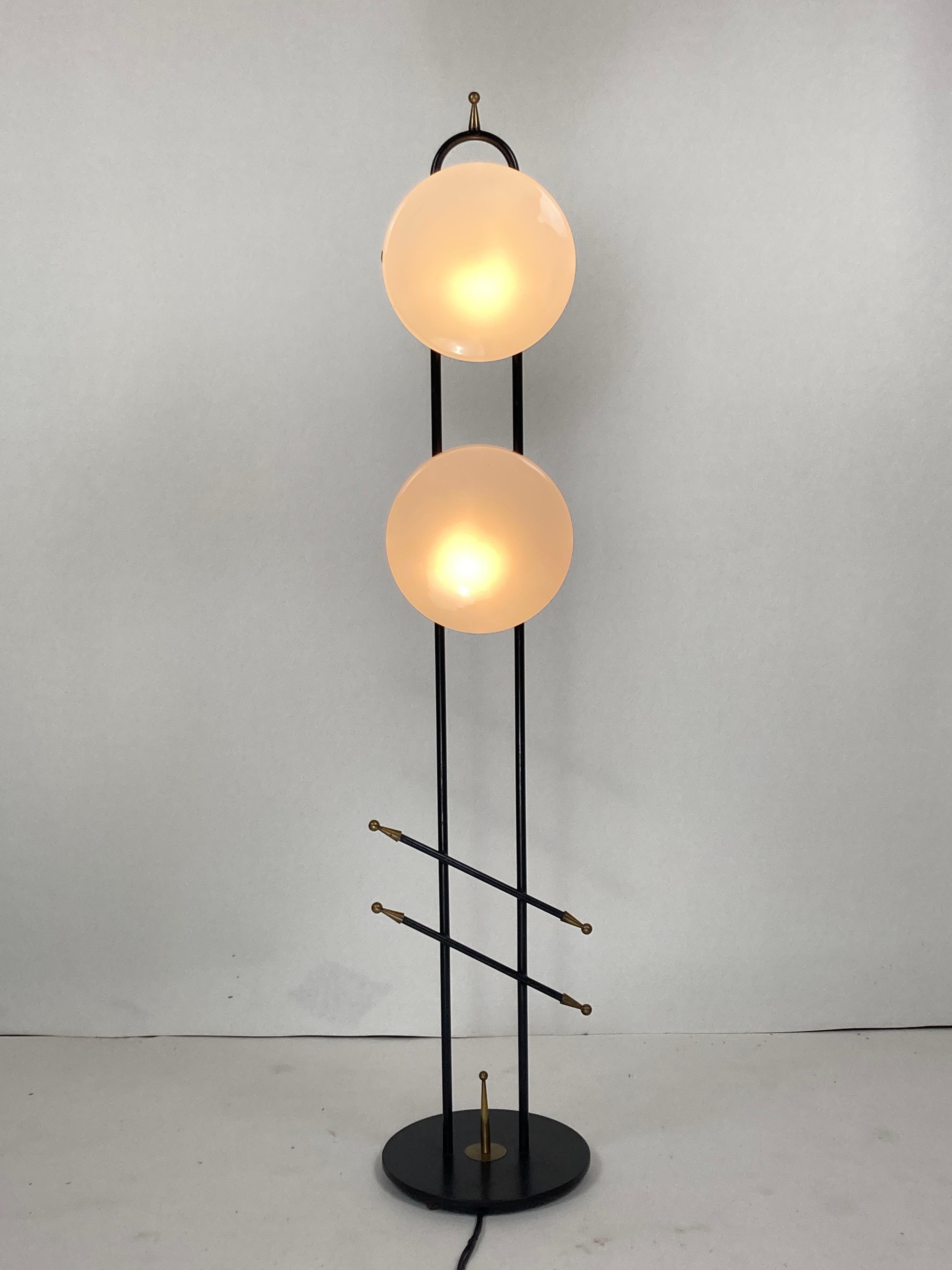 Wonderful and perfectly proportioned floor lamp by Maison Lunel from the 1950s - 1960s. The lamp in gilded brass and black lacquered metal supporting two opaline globes that are fixed by a sliding system, a system known to be used by Lunel, is in a