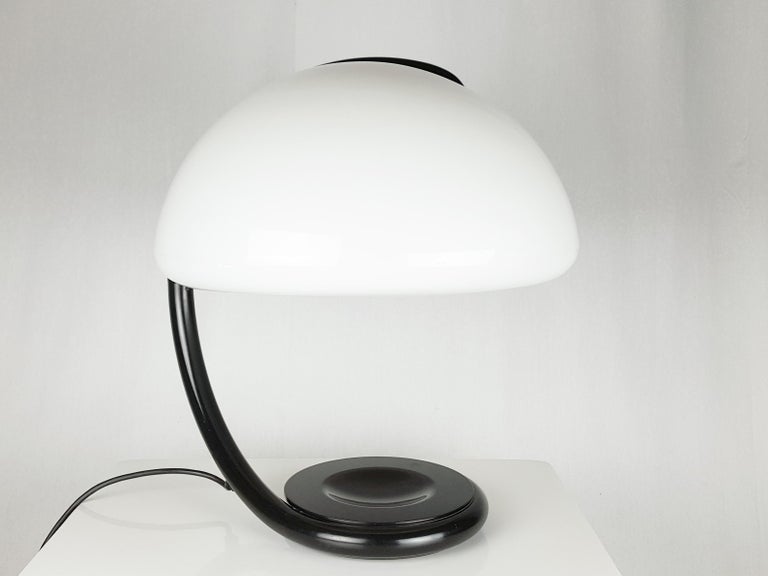 Black metal adjustable base with white plastic shade. Maker label inside the shade and above the base. 
The lamp remains in excellent condition; light scratches around the lampshade. When the arm is fully open, the lampshade slightly loses its