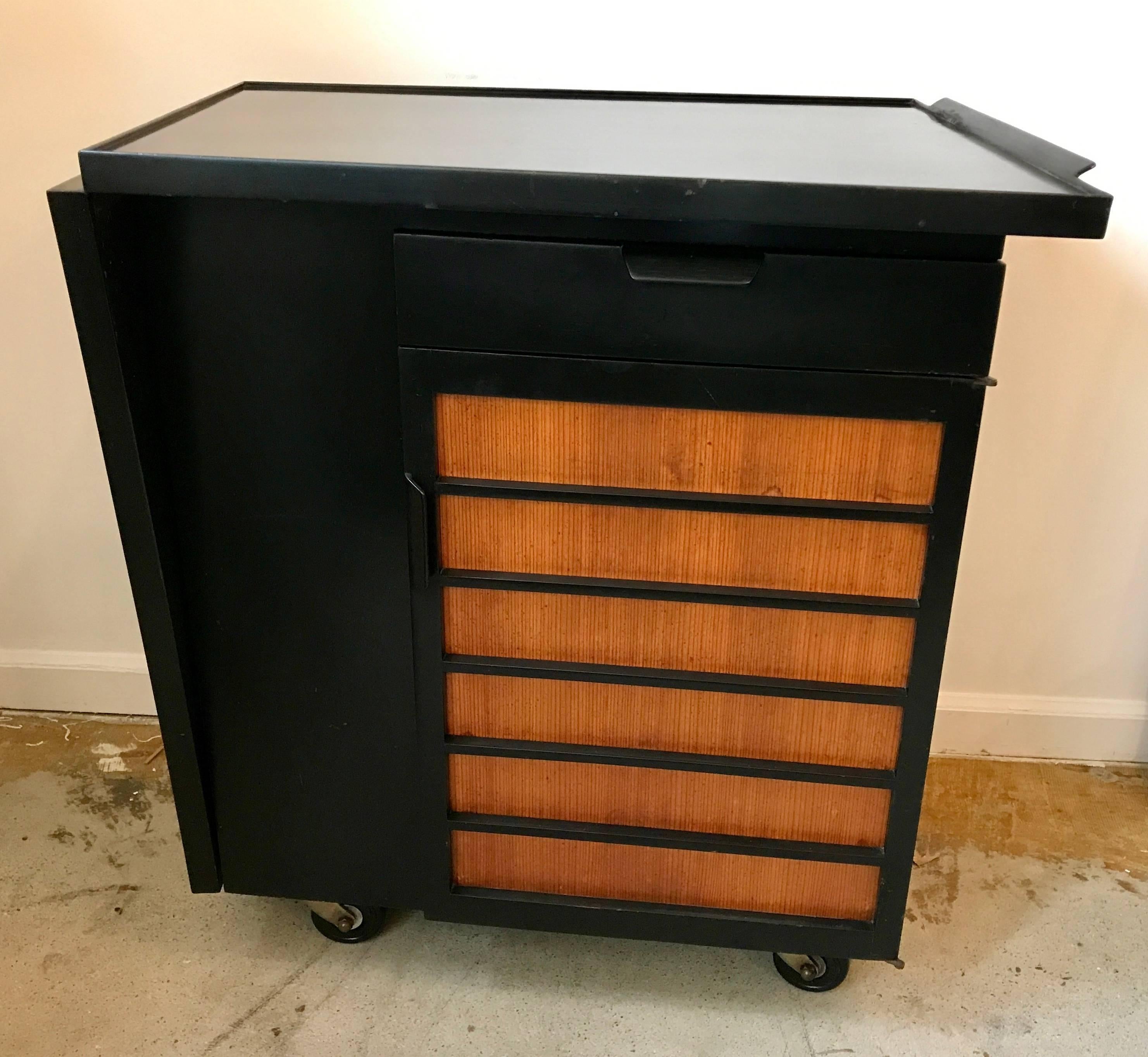 Very rare black Edward Wormley for Dunbar party server bar cart model 5433. This 1950s bar cart features one drawer and one door compartment concealing one adjustable shelve along with one 27-inch fold down tabletop extension. Tabletop measures 54