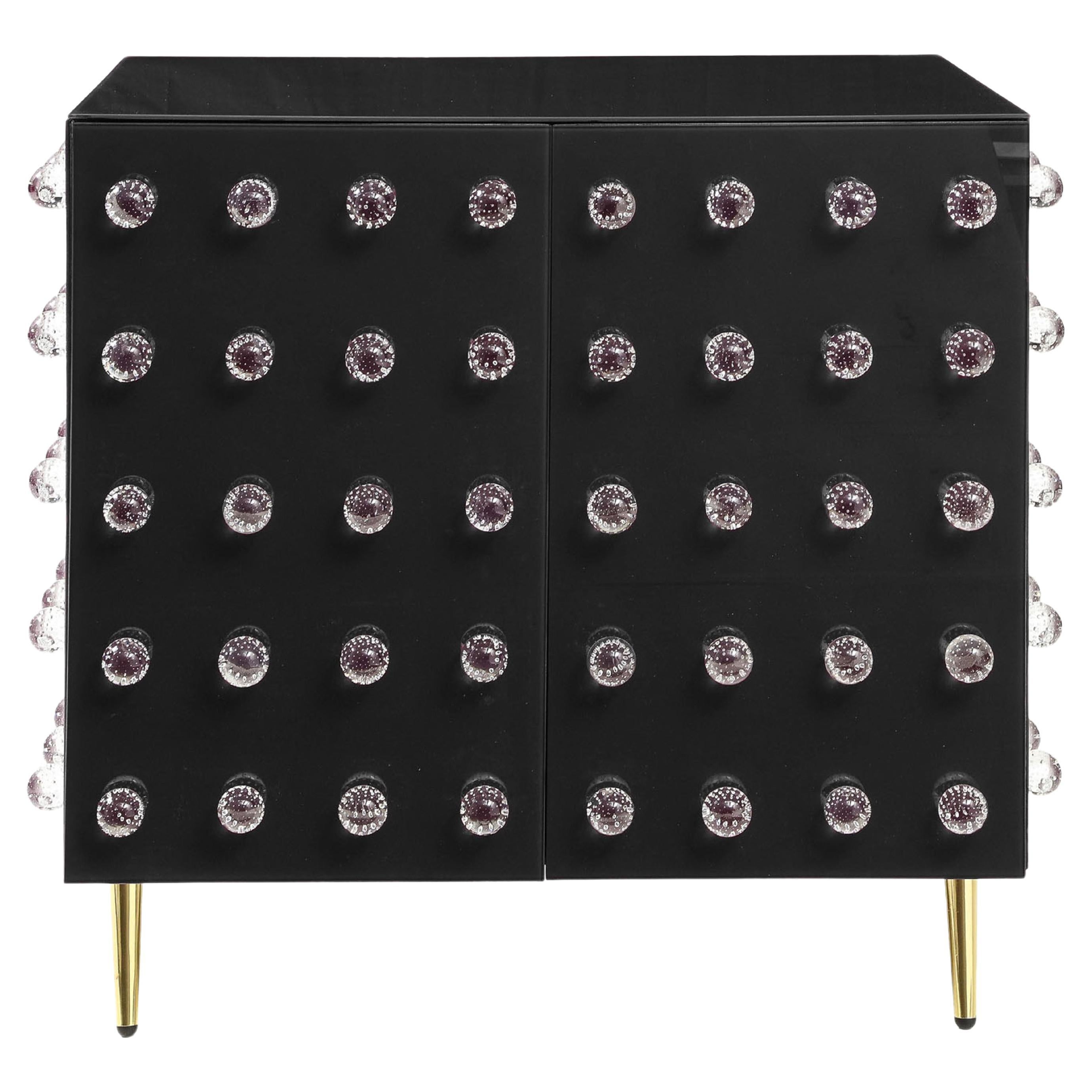 This sublime cabinet is a true work of art, handcrafted by expert Murano glassmakers blending ancient and modern styles. 

This cabinet features 90 exquisite Murano glass spheres decorating a rich black glass surface. 

Opulent brass feet complete
