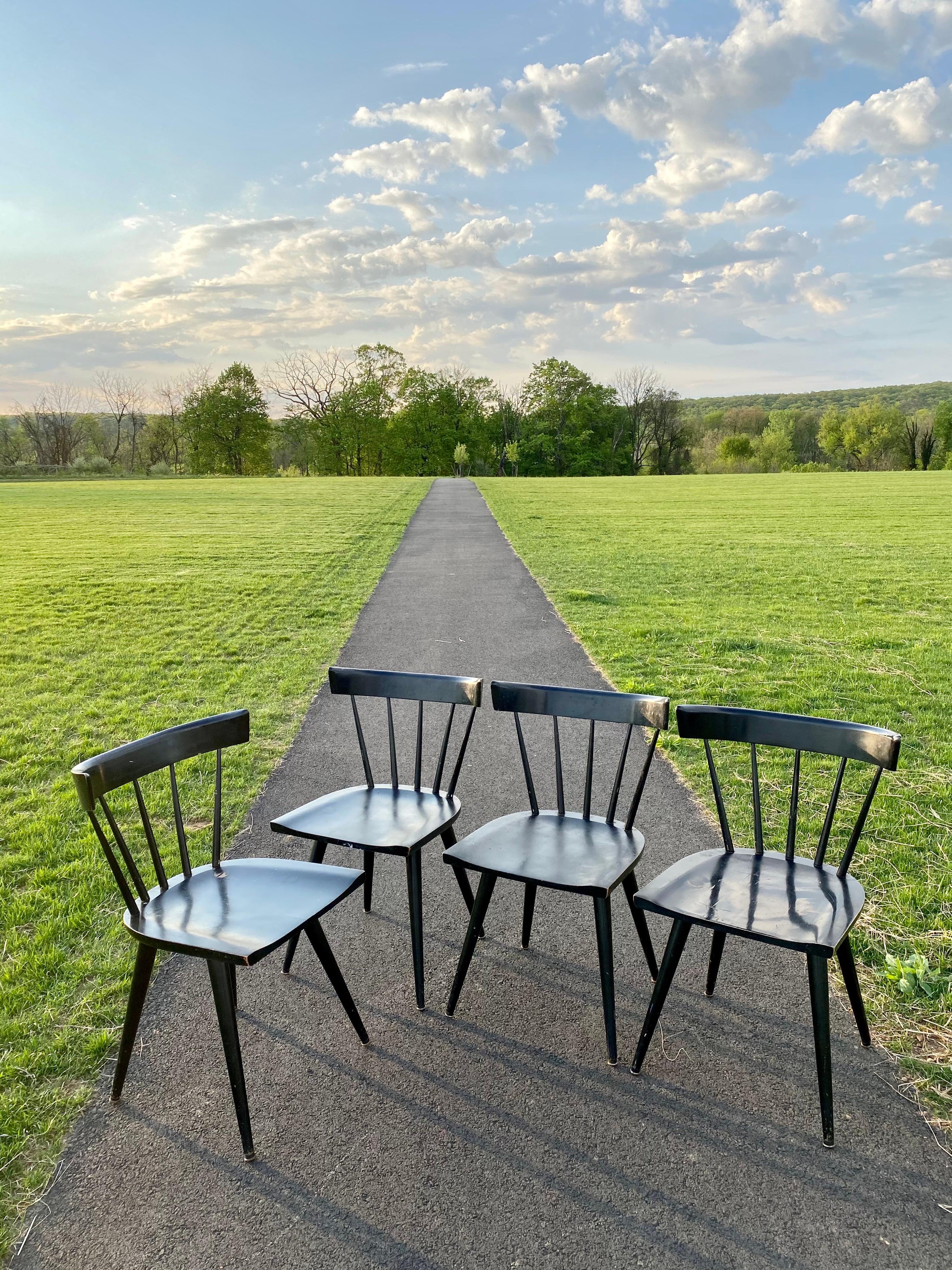 Set of four Mid-Century Modern Paul McCobb for Planner Winchendon dining chairs. These sleek Windsor style chairs feature curved backs, five rounded spindles, and all original black lacquer painted finish. Wonderful patina and wear to some corners