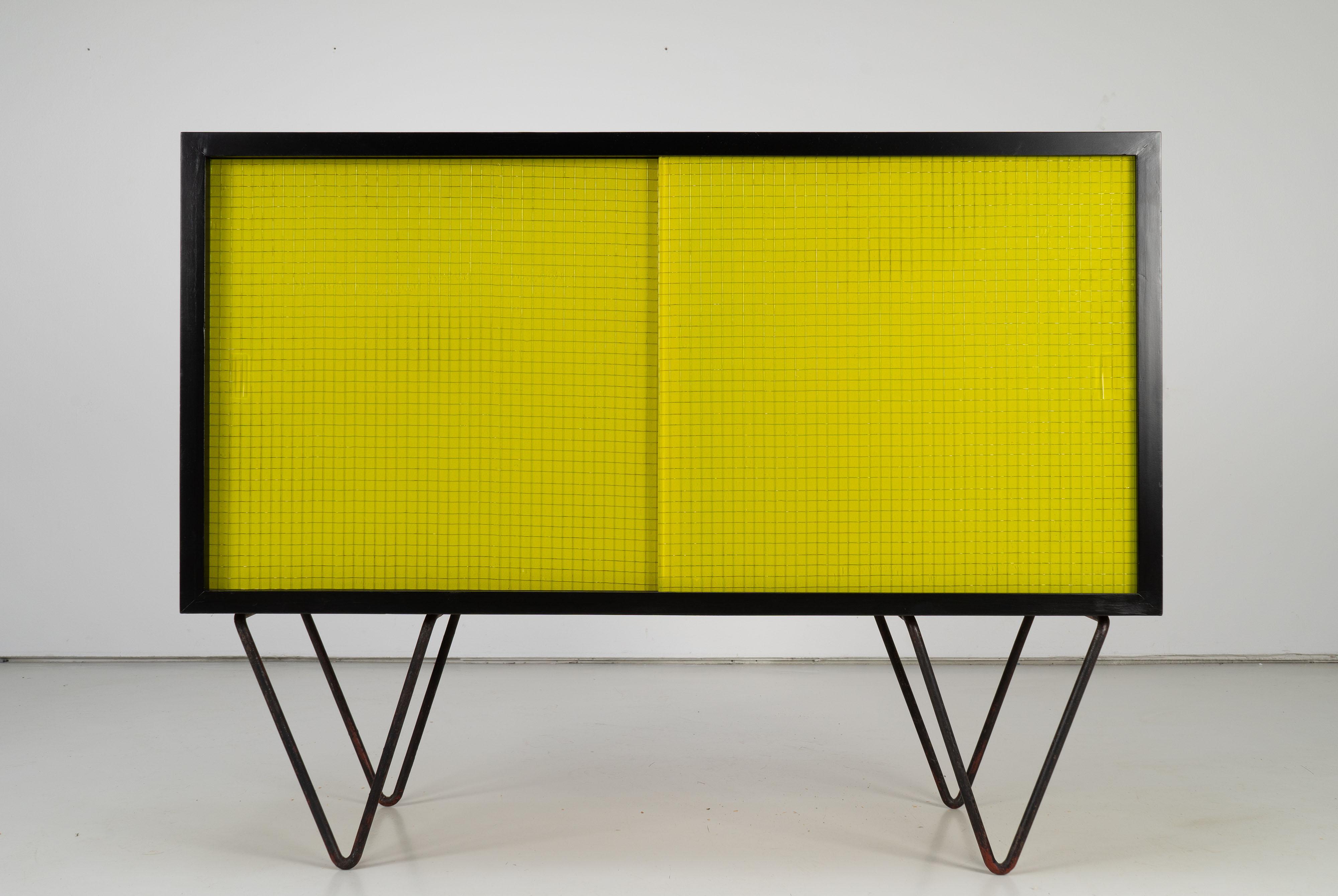 Vintage sideboard on steel feet from the 1950s. Black lacquered body with sliding doors made with faded yellow formica.