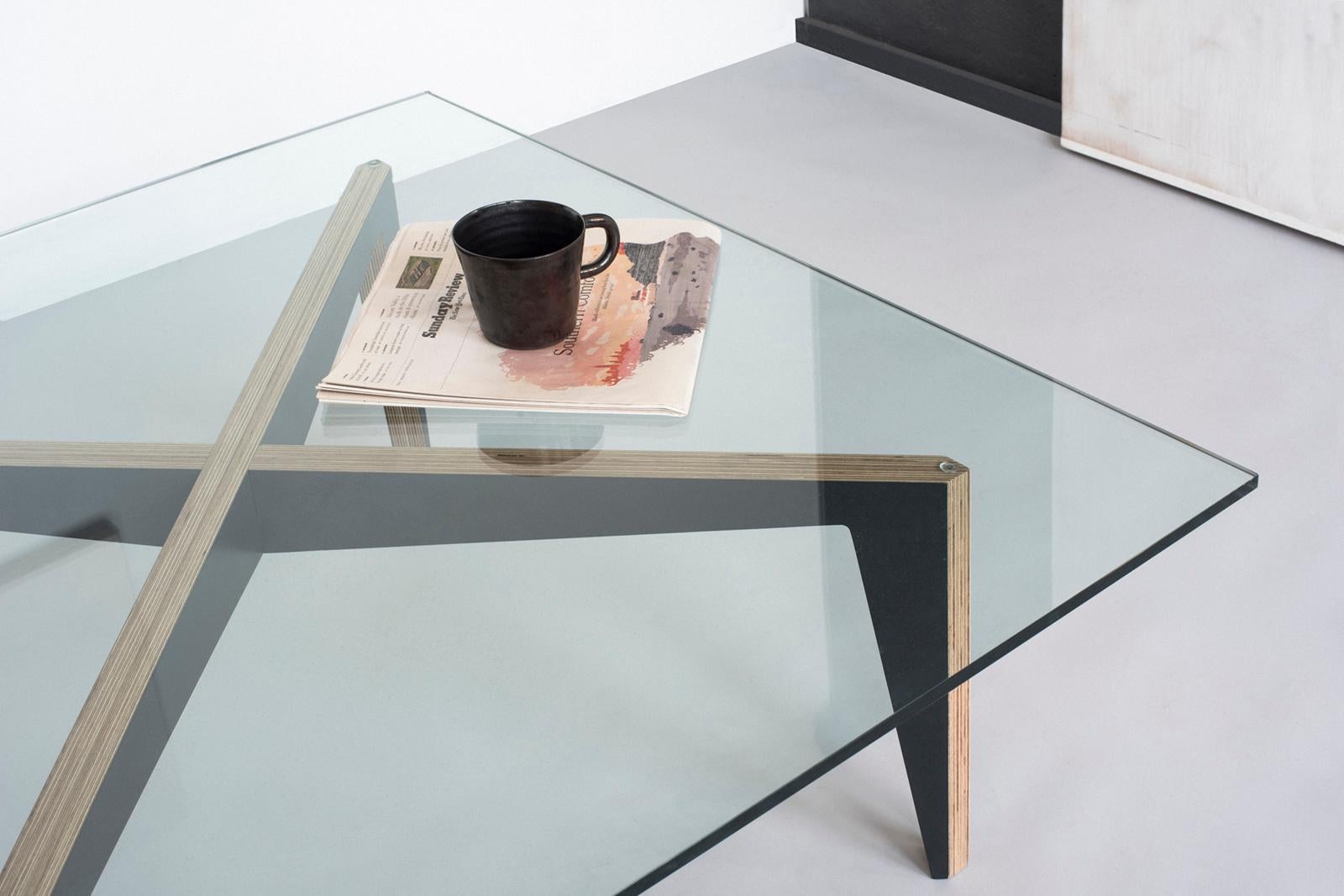 Cette table basse design minimaliste avec un plateau en verre est moderne et ludique. La précision de la menuiserie rend l'assemblage indolore tandis que la silhouette de la base en forme de croix capture la tension entre le mouvement et