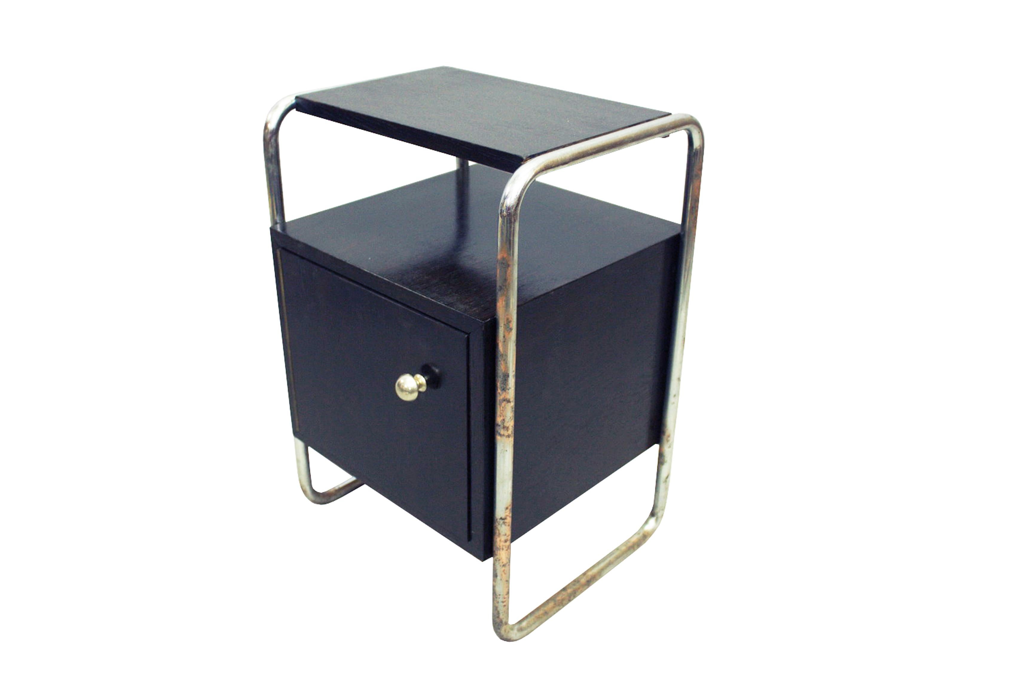 A black painted veneered cube cabinet fixed to chromed steel tubular frame loop on either side, this eye-catching bedside table is a lovely example of functionalism – a simple form yet memorable design typical of this era. There were many variations