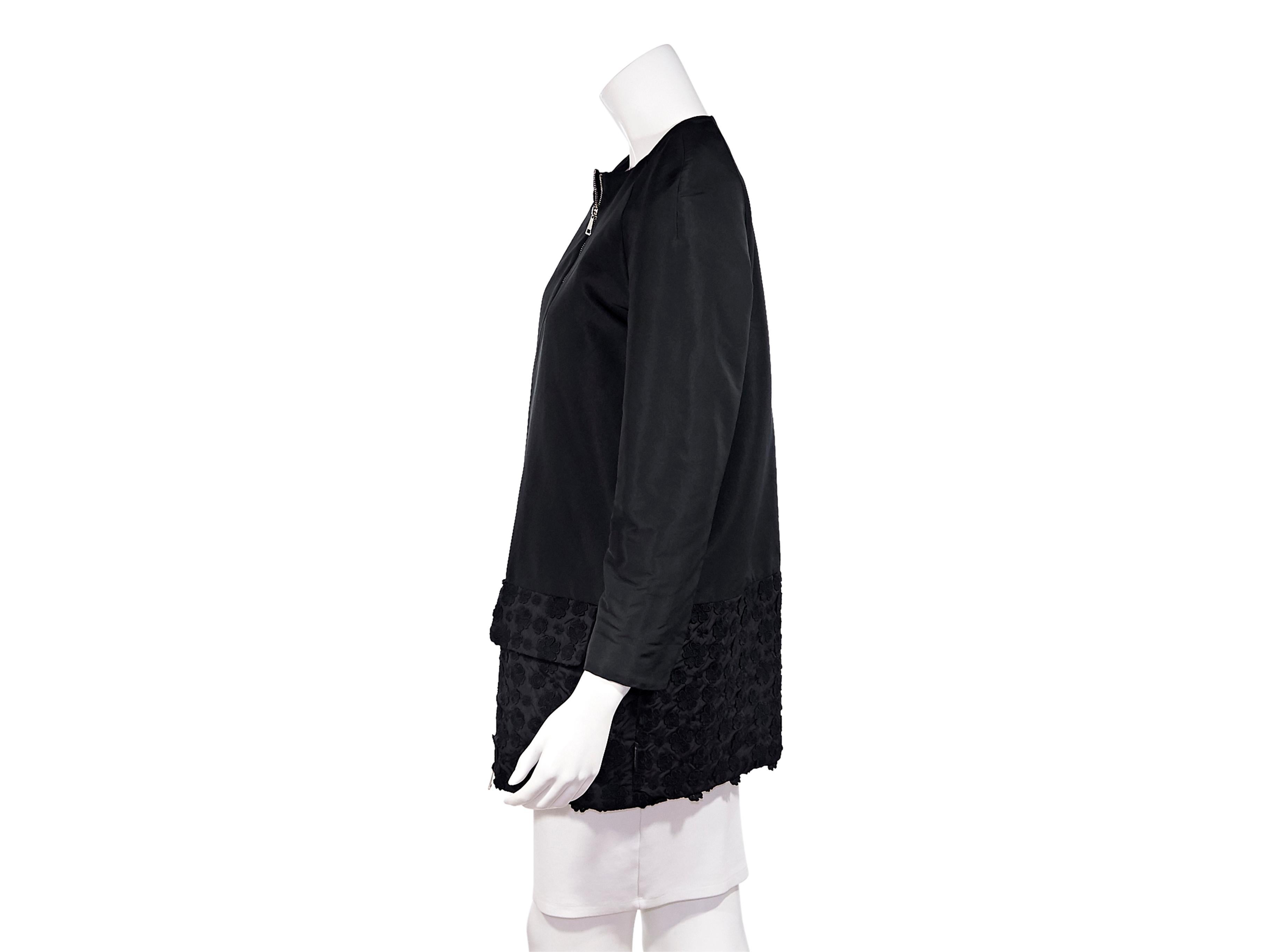 Product detail: Black cotton-shell coat by Moncler. Collarless. Cropped sleeves. Dual flap pockets at hips. Floral-embroidered at hem. Dual zip-front closure. Silver-tone hardware. Pair with a ruffled high-collar top to show off the neckline. The
