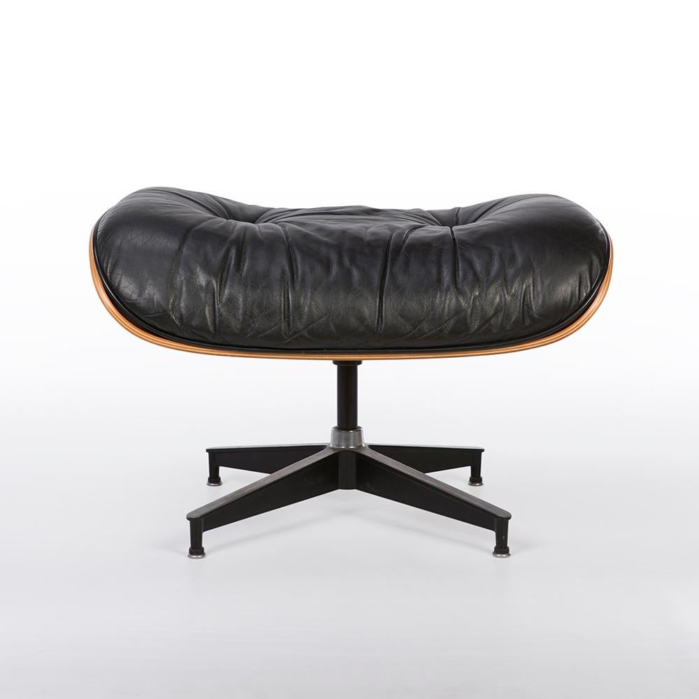 This is a used luxurious black and Cherry Herman Miller lounge chair and ottoman set completed with a rich cherrywood veneer, enclosed by a gorgeous black leather. It does, however, have a few scratches on the wood and small paint marks but