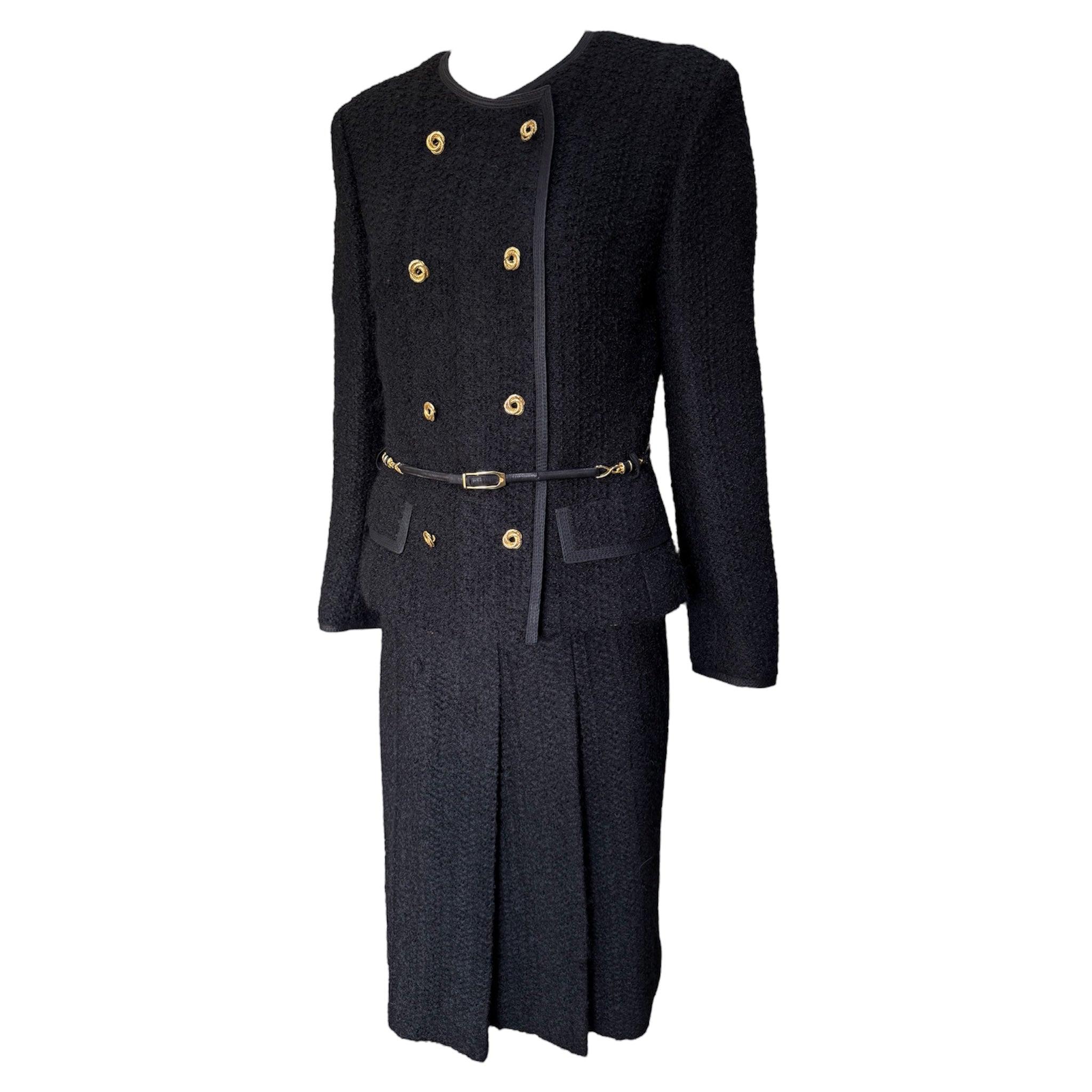 Oh so Jackie O! Timelessly chic early 1960's skirt suit, in the style of the classic Chanel wool bouclé suits. Inside, the jacket has the gold tone chain on the bottom.  Gold-toned coiled buttons decorate the double breasted silhouette. Black cord