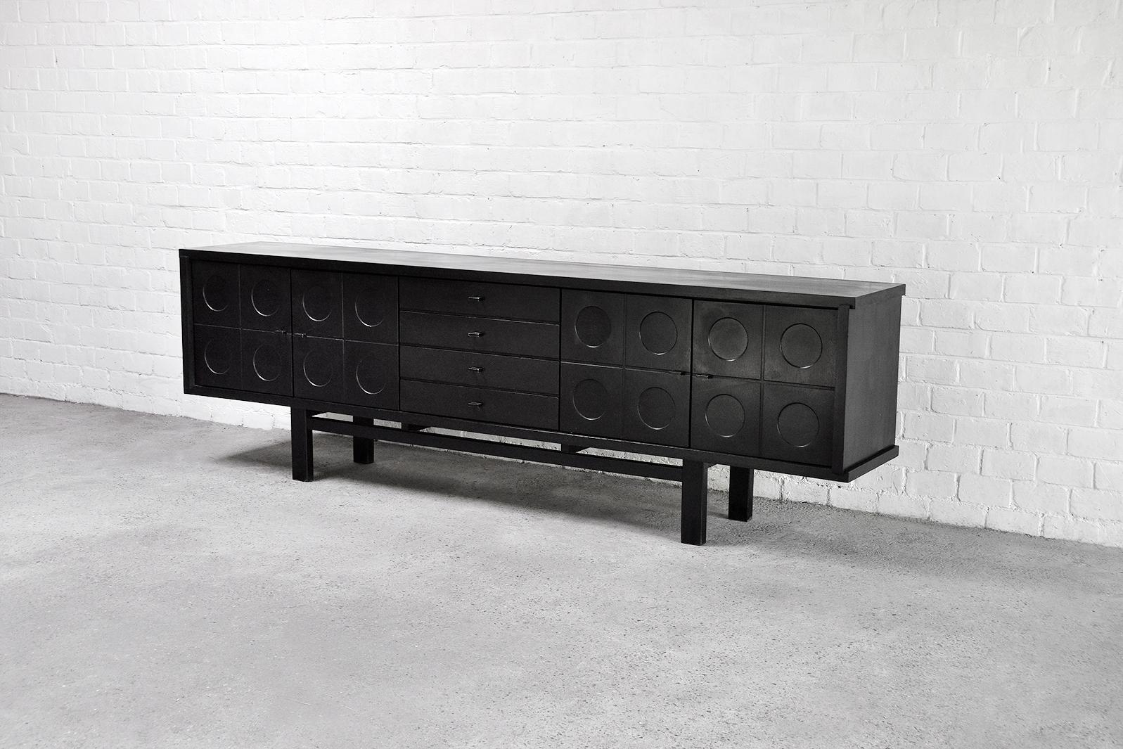 A stunning brutalist/modernist sideboard made out of ebonized oak, 1970s. Attributed to Belgian manufacturer ‘De Coene’. This sideboard features four decorative graphic door panels and four middle drawers. Thanks to the symmetrical leg structure,