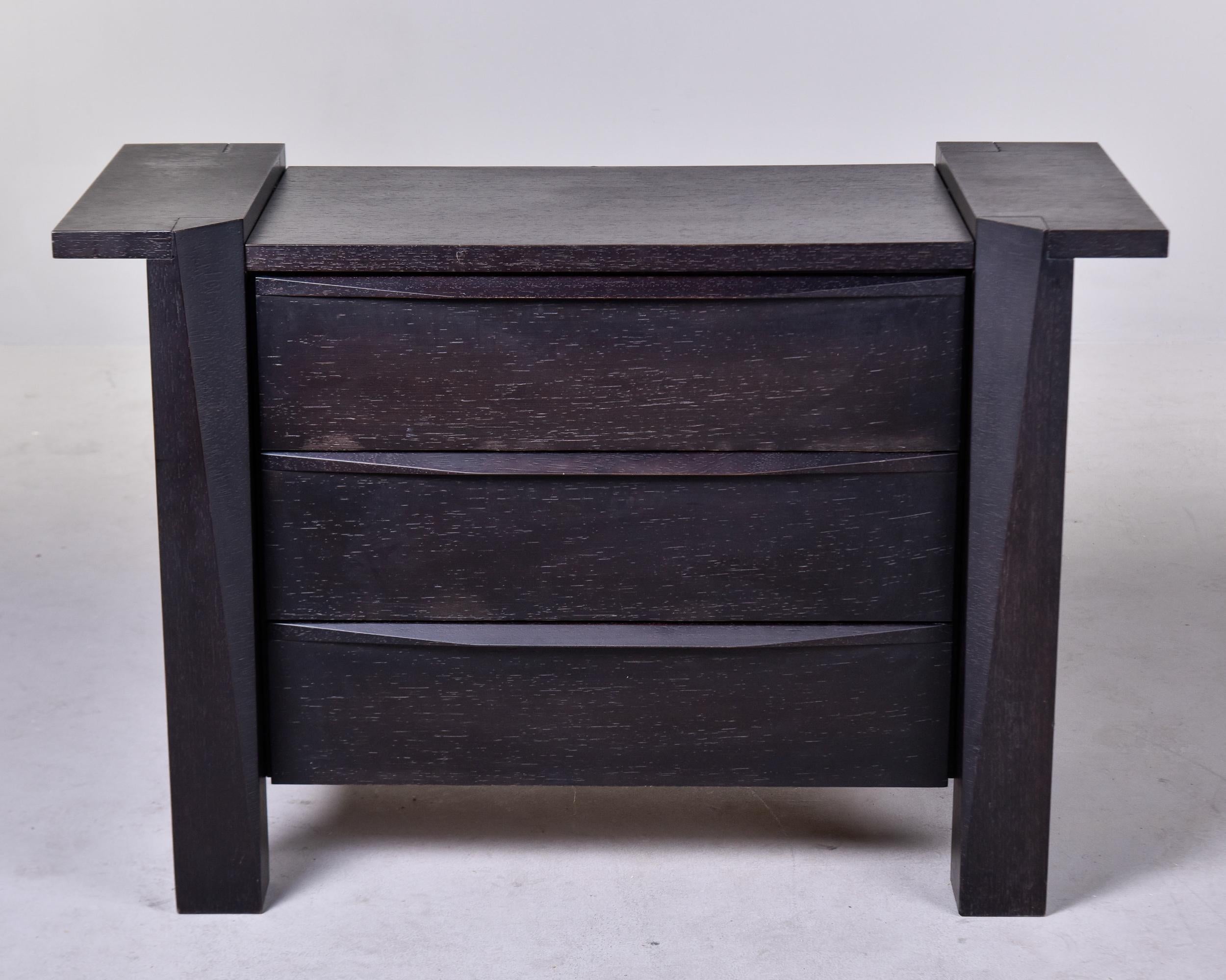 Found in Italy, this circa 1970 chest or commode has three drawers. Made of oak, this piece has a black finish and an unusual, sculptural shape with a flared sides at the top, built in drawer pulls and substantial legs. Unknown maker.