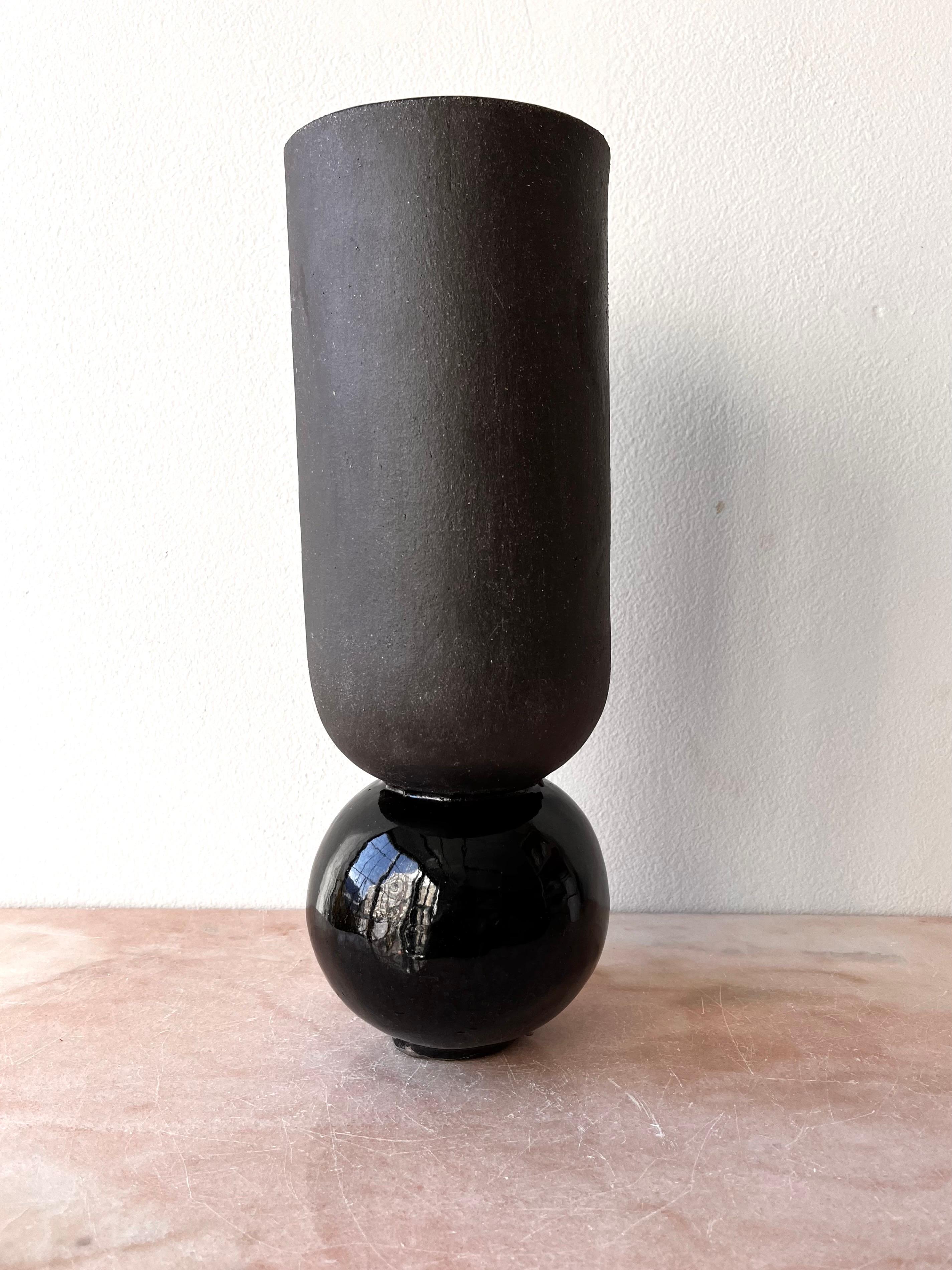 Slab-constructed vase, made with black stoneware which is glazed inside and on the base and unglazed on the main exterior for a matte-gloss contrast. It is open through to the bottom inside, so water will fill the round base.