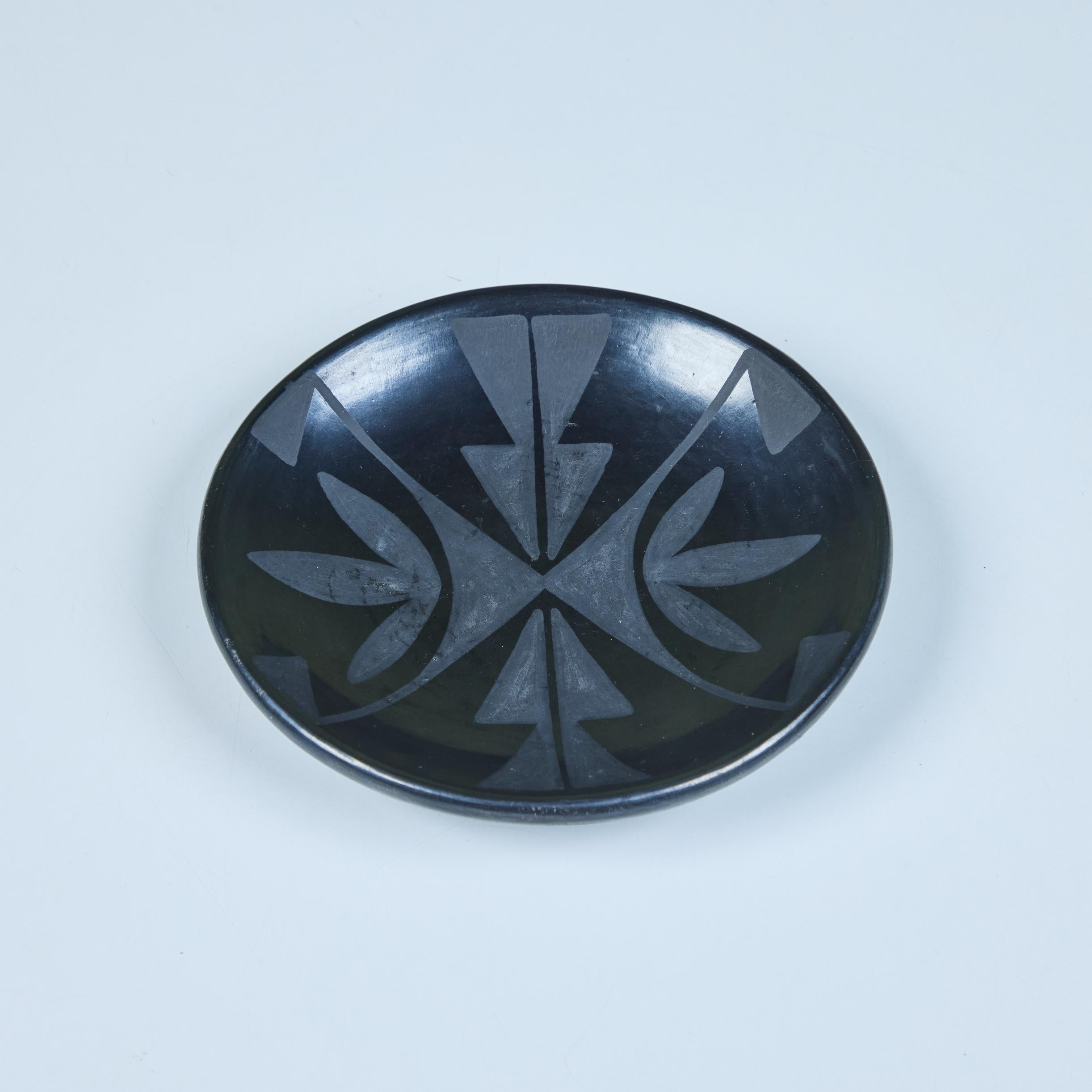 Plat en céramique de l'artiste potière amérindienne Maria Martinez et Santana c.1960. L'assiette ronde présente un style de poterie noir sur noir qui combine des surfaces noires mates et polies et dont Martinez et son mari ont été les pionniers au
