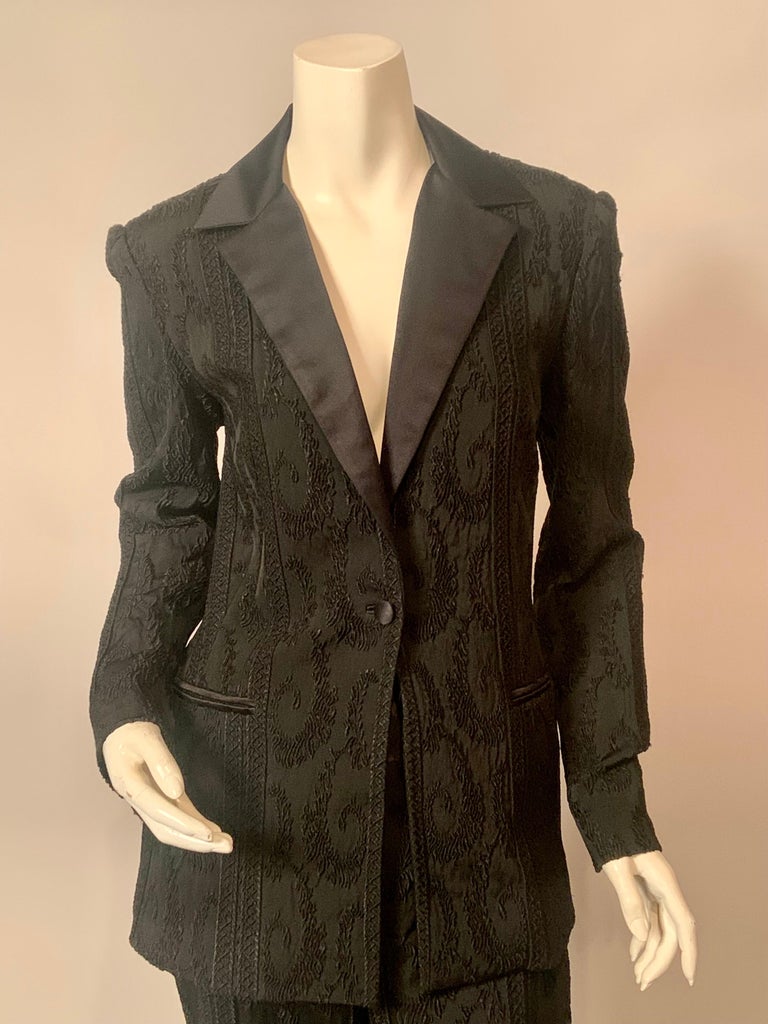 This chic black silk tuxedo is made from the most beautiful woven fabric with swirling curved designs and vertical bands in the textured design.   The jacket has classic notched satin lapels, button and pocket edges.  The pants have a wide band of