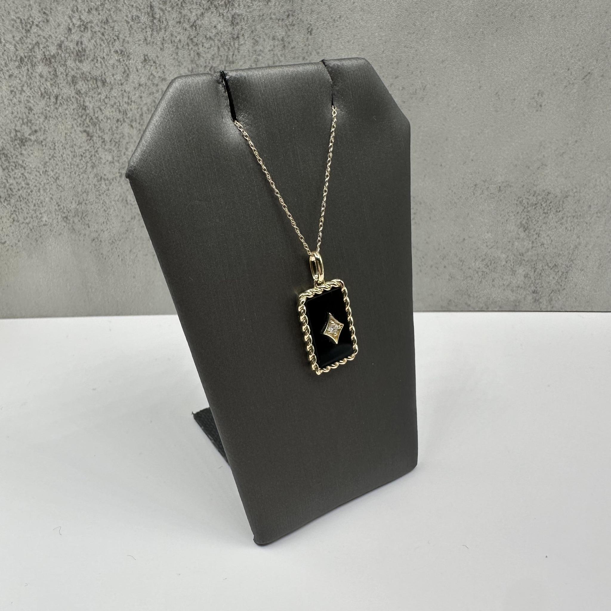 Este llamativo collar de ónice negro y diamantes en oro amarillo de 10 quilates presenta una atrevida pieza central de ónice negro acentuada por 0,06 quilates de peso total de diamante redondo GH SI natural. El profundo contraste entre el rico ónice