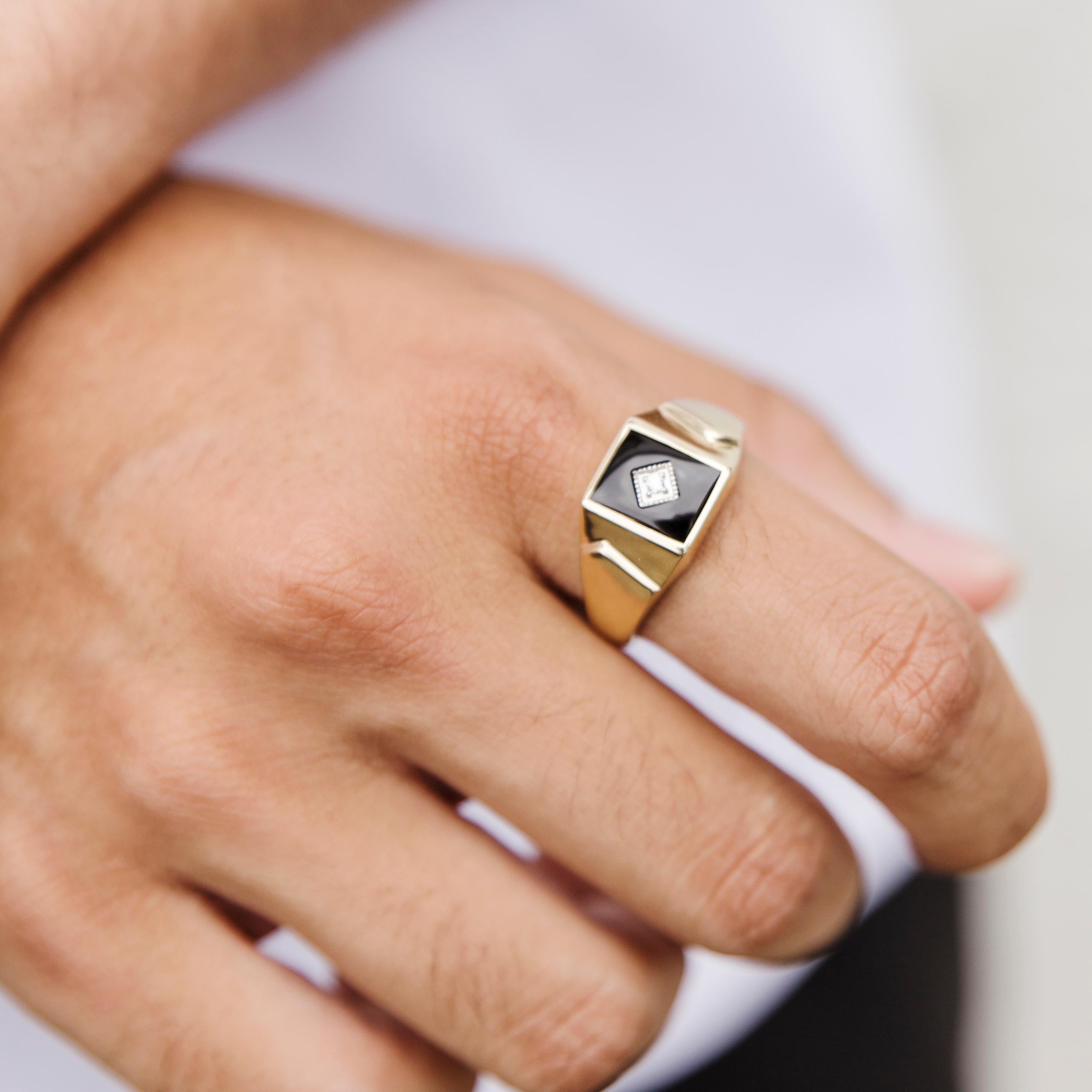 Forged in 9 carat yellow gold, this distinctive men's signet ring features a high polish band flowing out into a raised flat top set with a black rectangular onyx and a sparkling round diamond in the centre. This dapper vintage men's signet ring is