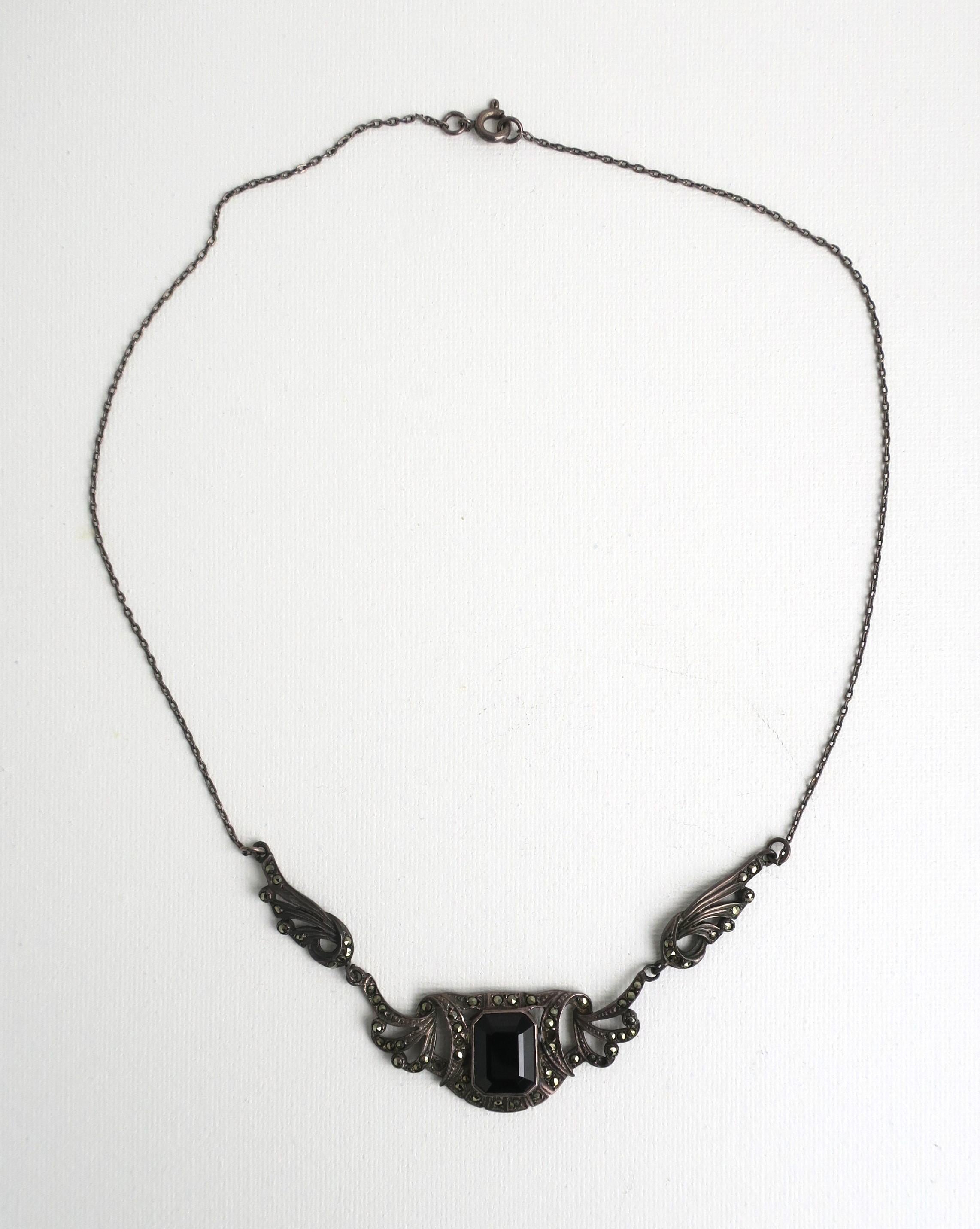 A sterling silver and black onyx necklace, in the Art Nouveau style, circa late-20th century. Necklace has a nice sized black onyx center stone. Necklace looks beautiful around neck as demonstrated in fourth image. Necklace is shown unpolished which