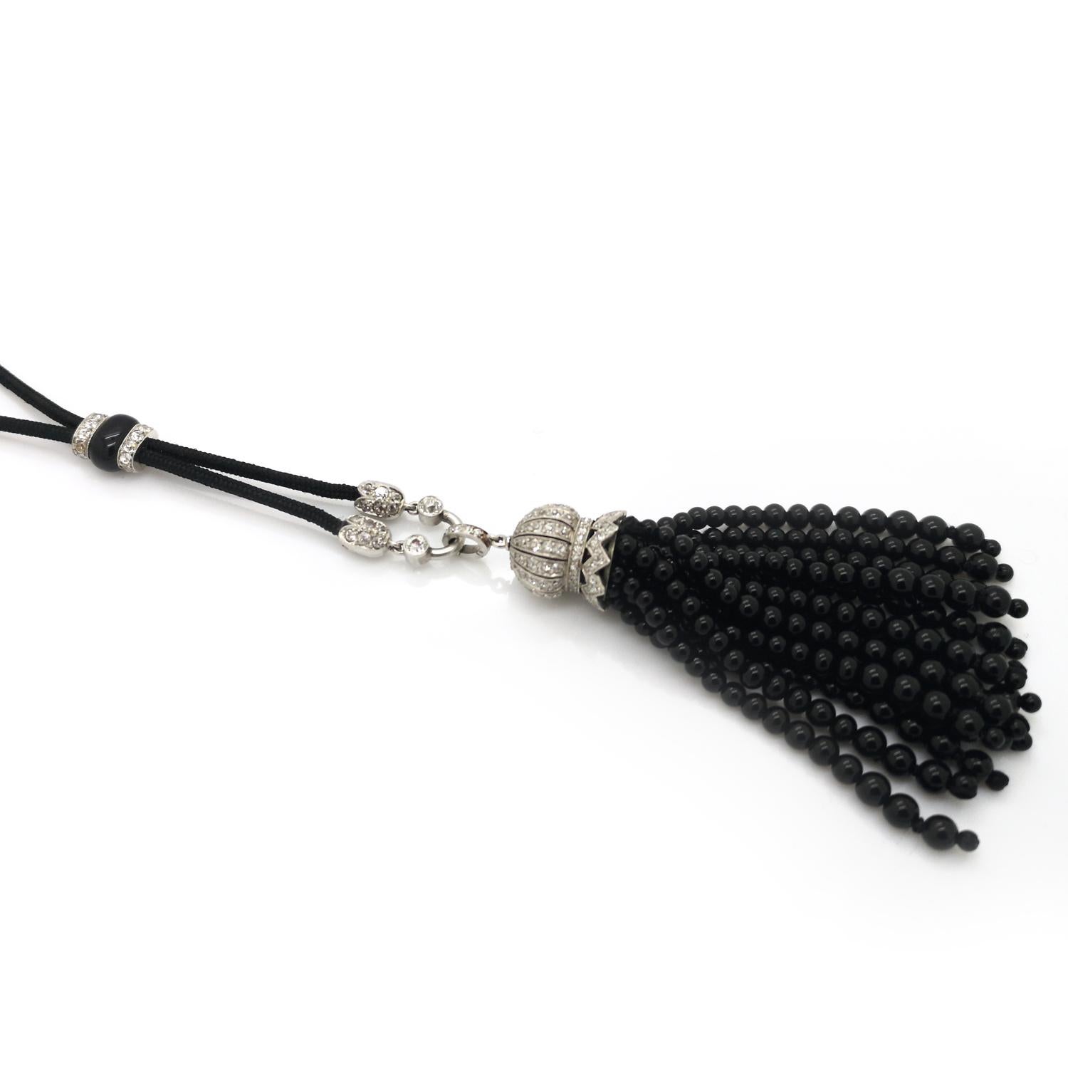 An Art Deco black onyx tassel pendant necklace, comprising of multiple rows of graduating black onyx beads, hanging below a brilliant-cut diamond set domed cap, and an old-cut diamond set terminal, mounted in platinum, attached to black cord,