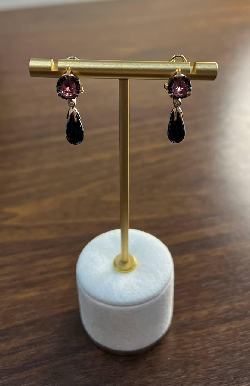 These elegant drop earrings feature a striking combination of black teardrop-shaped onyxes and rectangular faceted garnets set in a 14K Rose Gold frame.