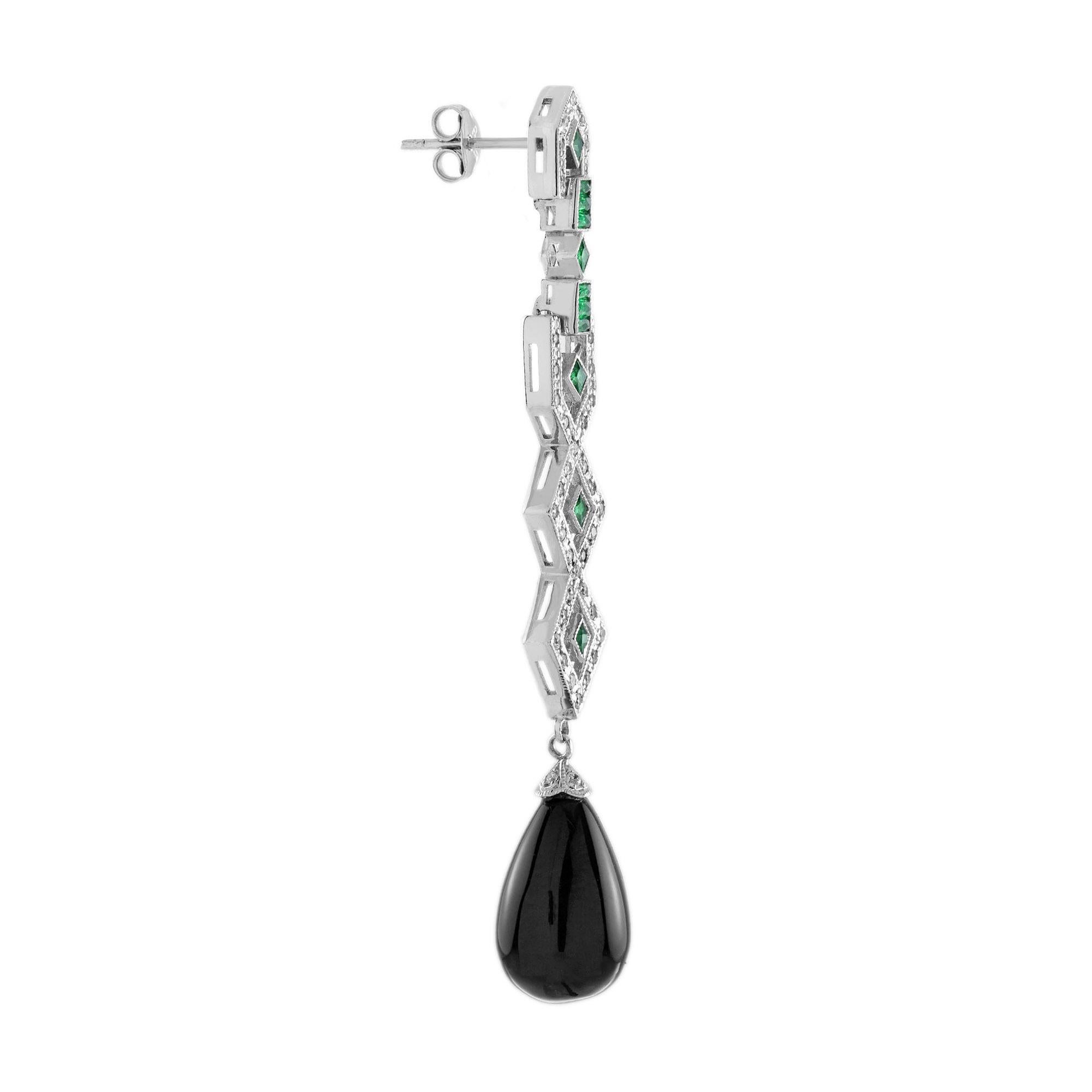 Ces boucles d'oreilles de style Art déco en or blanc 18 carats, composées d'onyx noir, d'émeraudes et de diamants, sont un mélange éblouissant de sophistication et d'allure. Les gouttes d'onyx noir frappantes créent un contraste audacieux, tandis