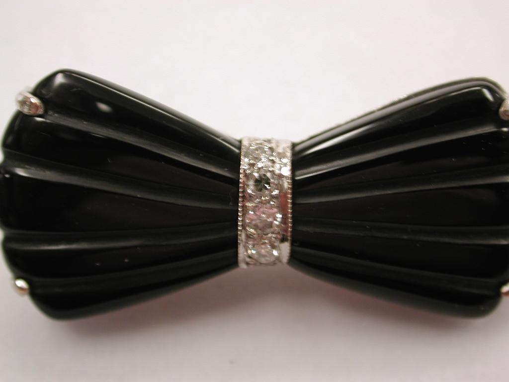 Black Onyx  Bow Brooch Mounted in 9ct White Gold dated circa 1930's
Set with old cut diamonds in centre of bow.
Onyx is striated to make it look more like a bow. 