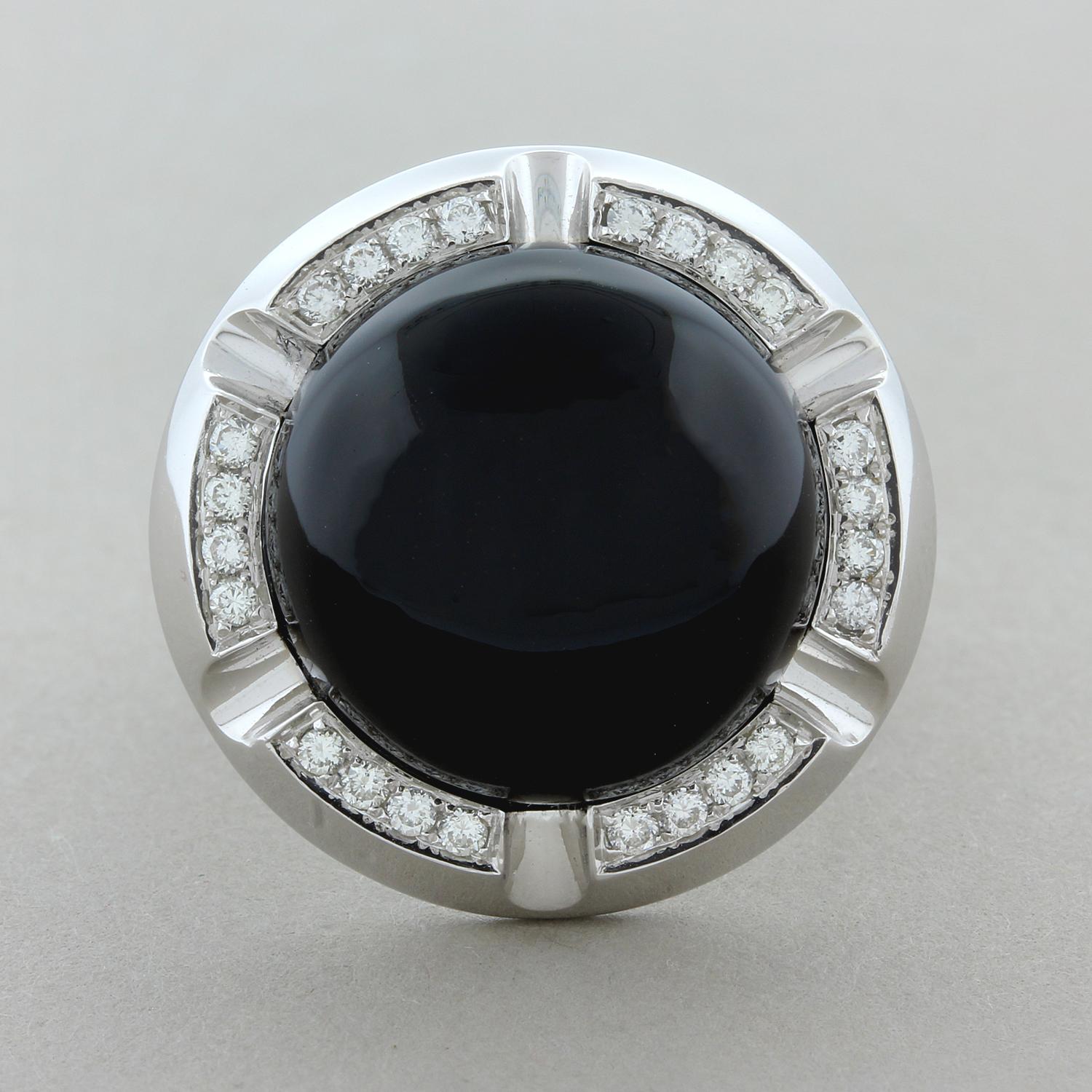 A lovely ring featuring a 17.60 carat piece of sleek black onyx with great luster. The onyx is haloed by 0.30 carats of round brilliant cut diamonds set in 18K white gold. There is great contrast between the deep black onyx and the bright sparkling