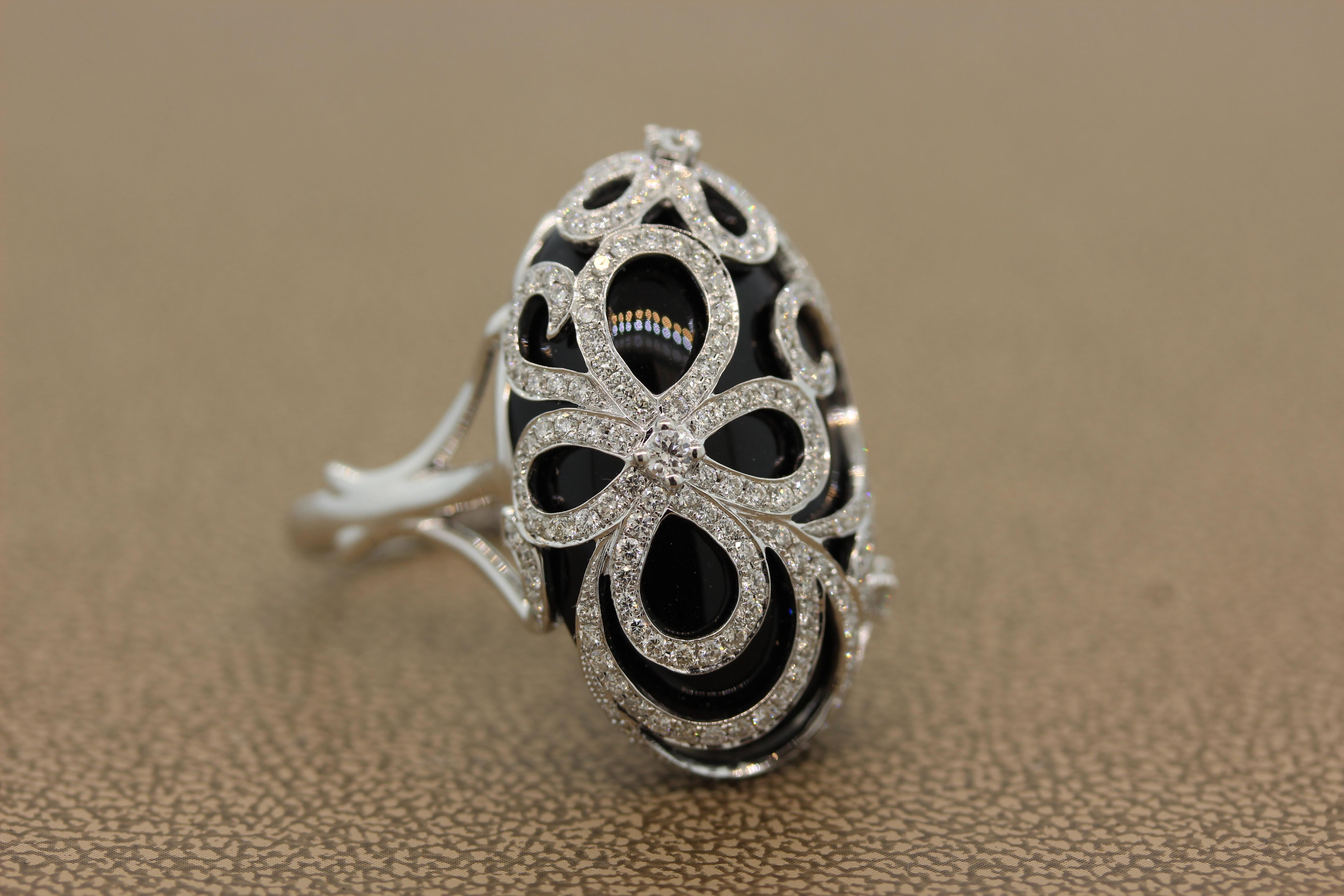 A bold and elegant cocktail ring featuring an oval shaped black onyx. The smooth glistening onyx is topped with a filigree lace of round cut diamonds. The 1.46 carats of VS quality diamonds are set in an 18K white gold setting creating an armature