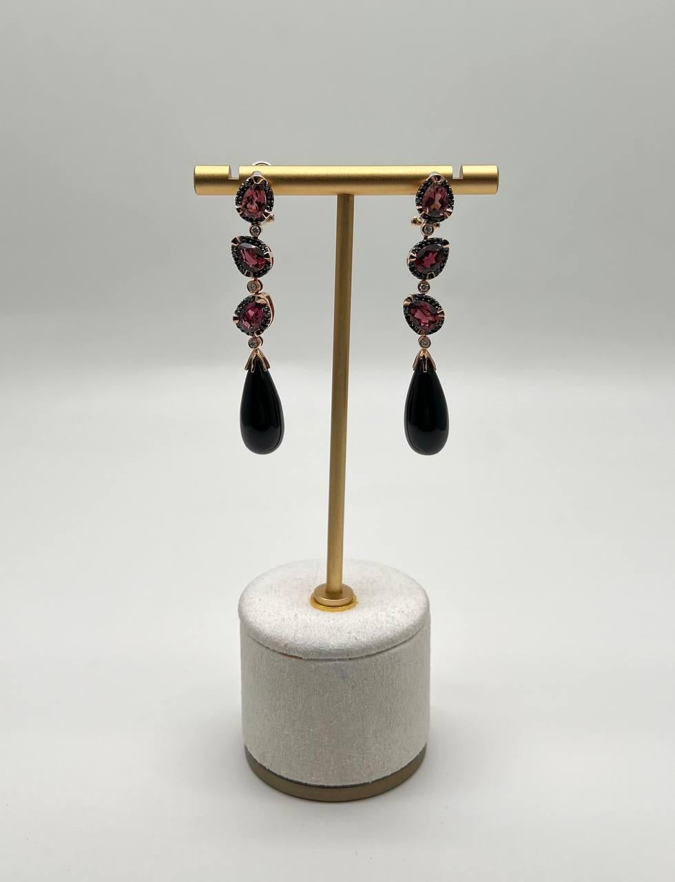 Discover the elegance of our exquisite drop earrings, a testament to refined craftsmanship.

These earrings feature a captivating design with rich, dark teardrop black onyx =that dangle gracefully. Above, a trio of shimmering garnets is set in a