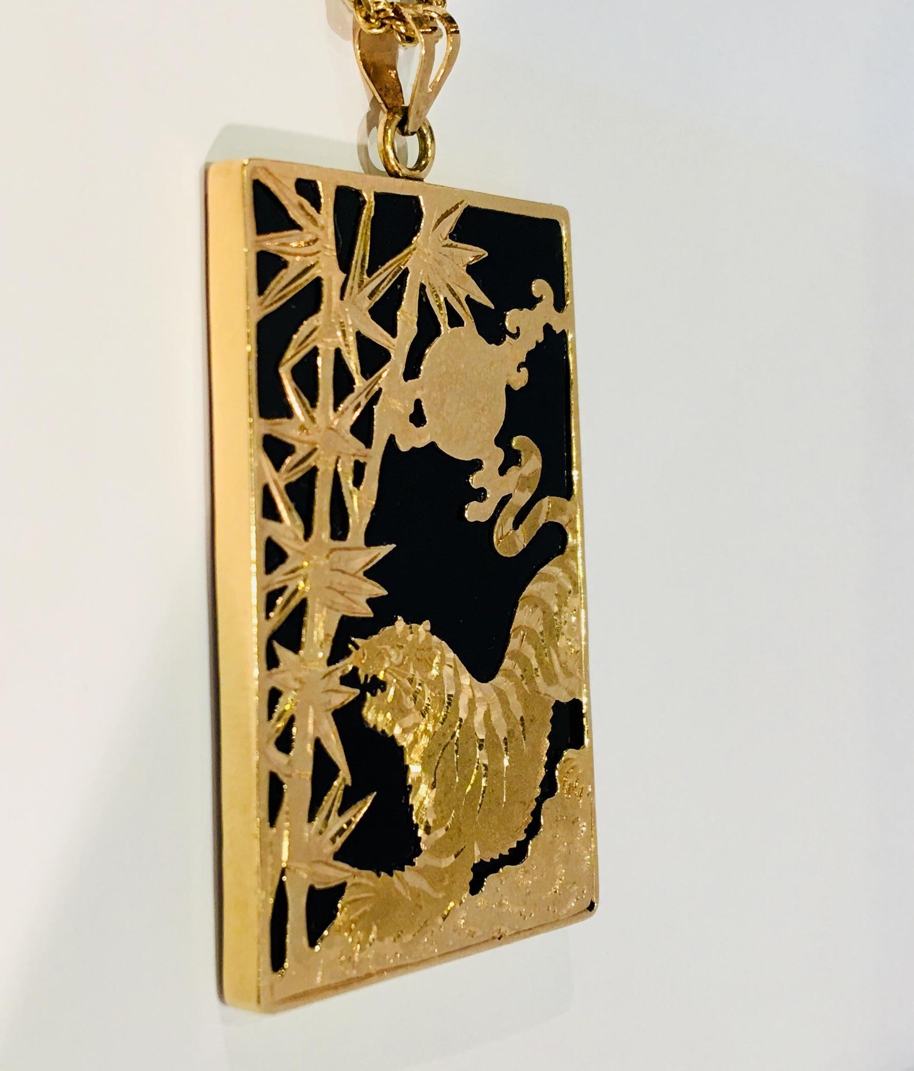 Large rectangular black onyx estate pendant is bezel set in 14 karat yellow gold and depicts an Asian-inspired scene of an open mouthed tiger facing two bamboo stalks by the light of a full moon.  

Associated with the moon and the lunar cycle in