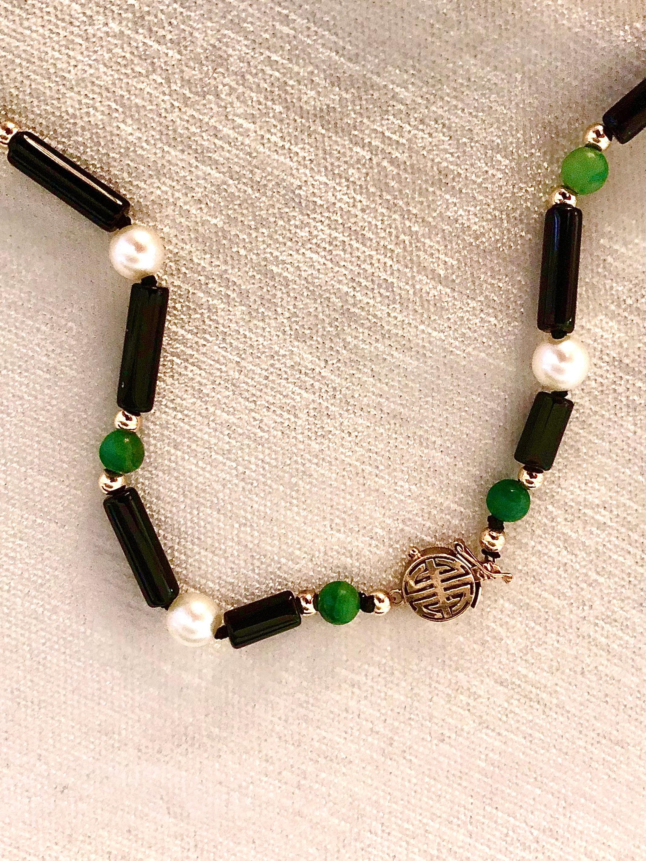 Delicate exquisitely simple convertible necklace.
Tubular onyx links are divided by alternating stations of lustrous white pearls and green jade beads flanked with smooth 14kt gold rondelles.

Suspended from an open circle of black onyx is a lovely