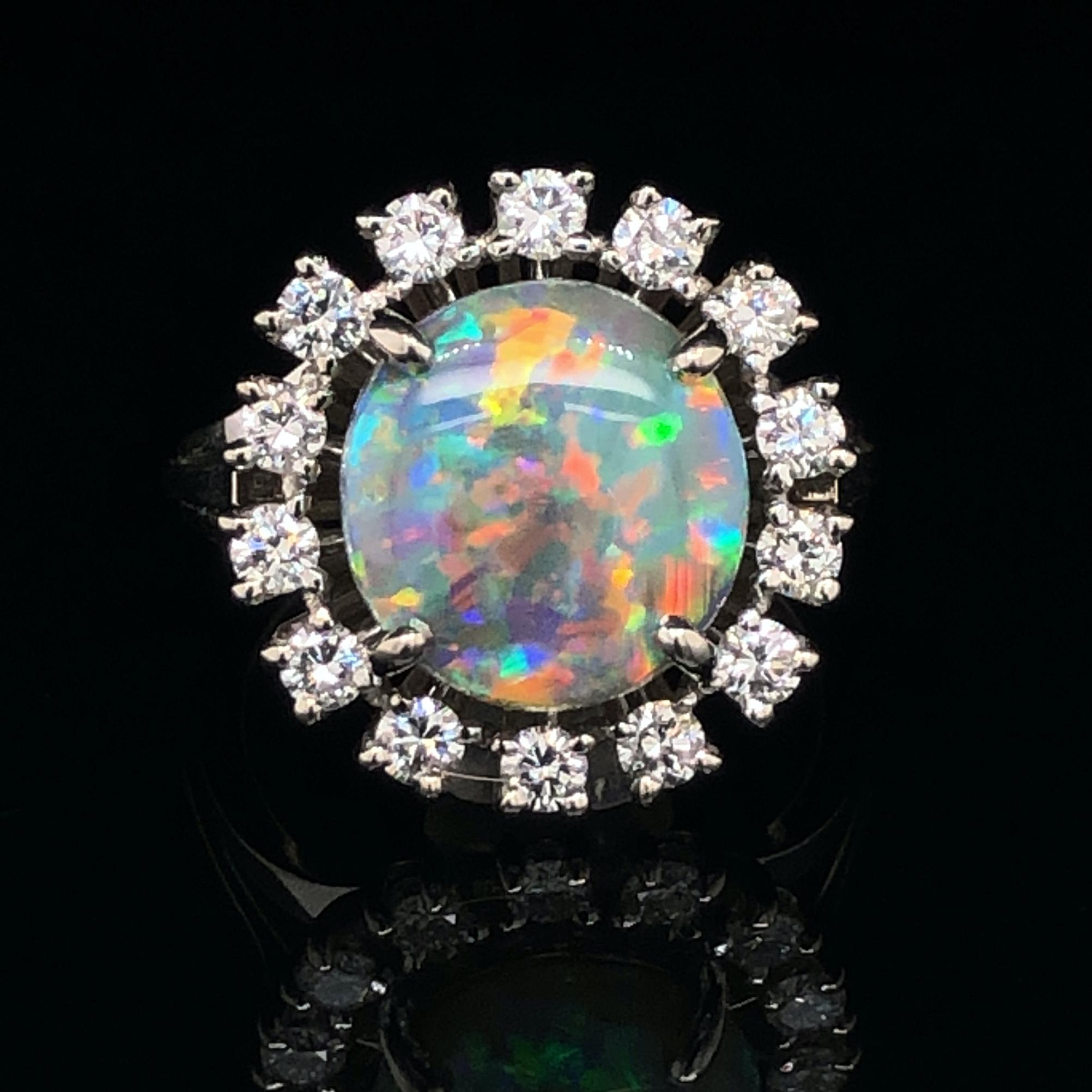 A fascinating black opal and diamond ring in white gold by Meister. The opal has a stunning play of colour and fire, with a lot of red flashes. All colours have a strong and deep shade. Thus the resulting pattern is very harmonious and magical. The
