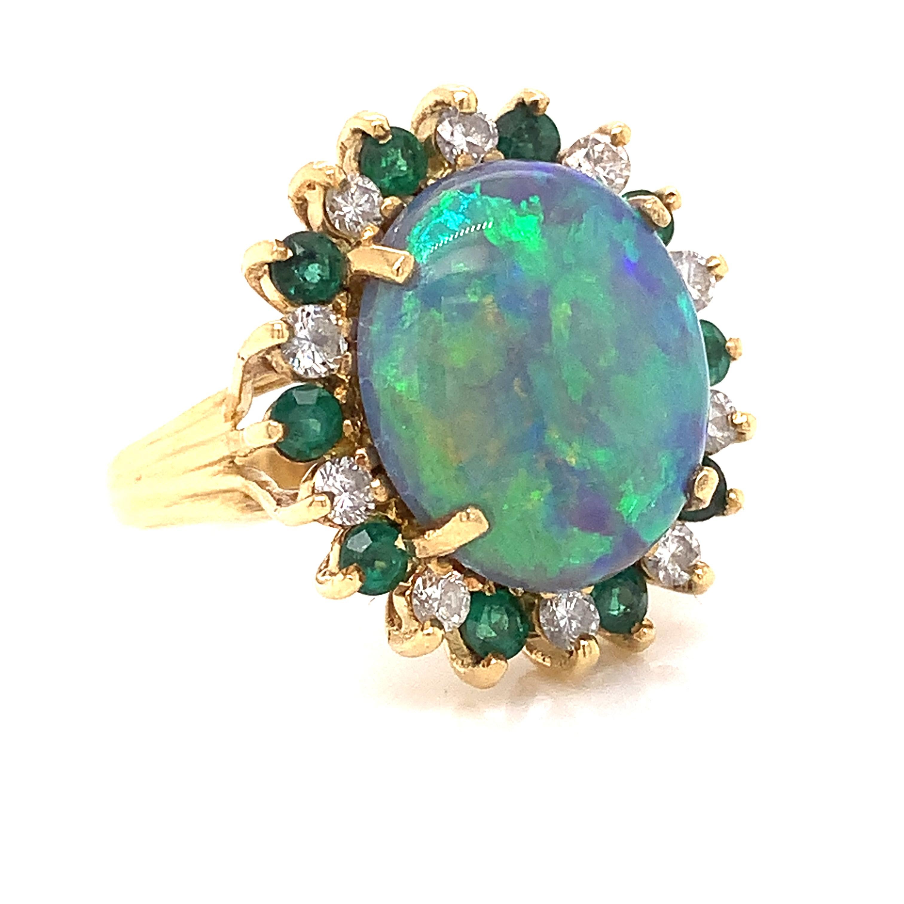This stunning dark blue and green Black Opal is 4.71 carats.  It is surrounded by ten SI clarity, G-H color round diamonds, one cttw.  Also surrounded by ten round emeralds equal to one cttw.  This ring is set in four grams of 18 Kt yellow gold.  