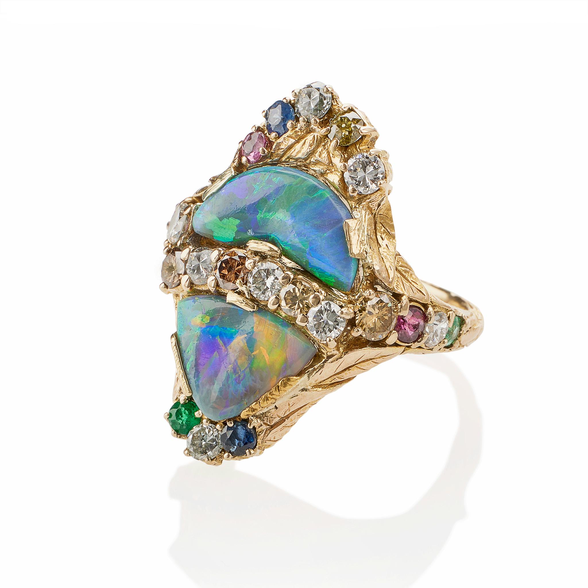 Created in the 1930s-1940s, this 14K gold ring is set with black opals and a variety of diamonds, colored diamonds, and colored stones. Centering two shaped black opal cabcohons, the mounting is further enhanced with circular-cut green garnets,