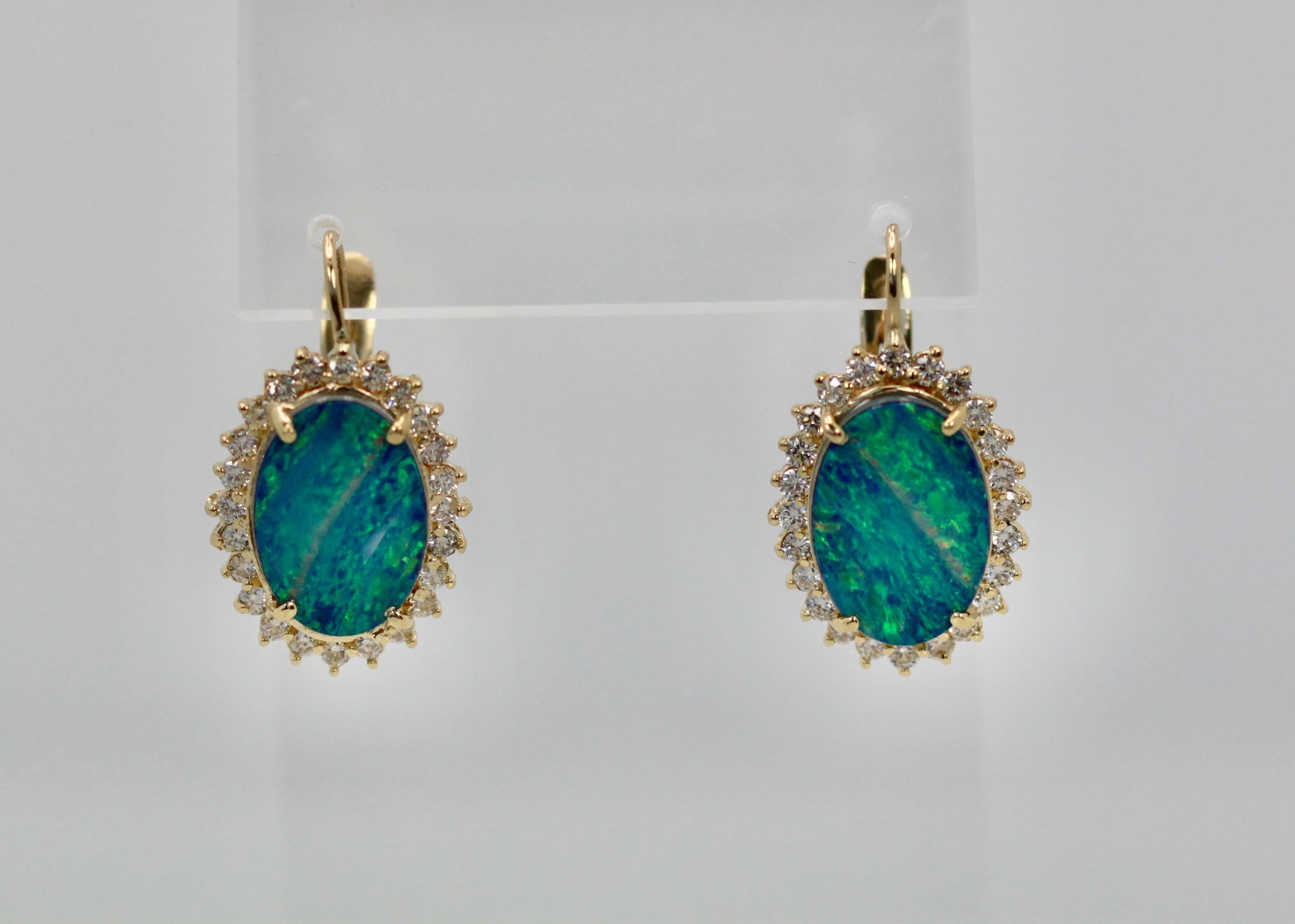 Diese Black Opal Ohrringe sind oval und mit einem Diamanten umgeben.  Die Opale sind 18,54 mm x 13,08 mm groß, es handelt sich um Opal-Doubletten. Sie sind mit Diamanten umgeben und messen 23,26 mm x 17,51 mm.  Diese wiegen 10,2 Gramm und enthalten