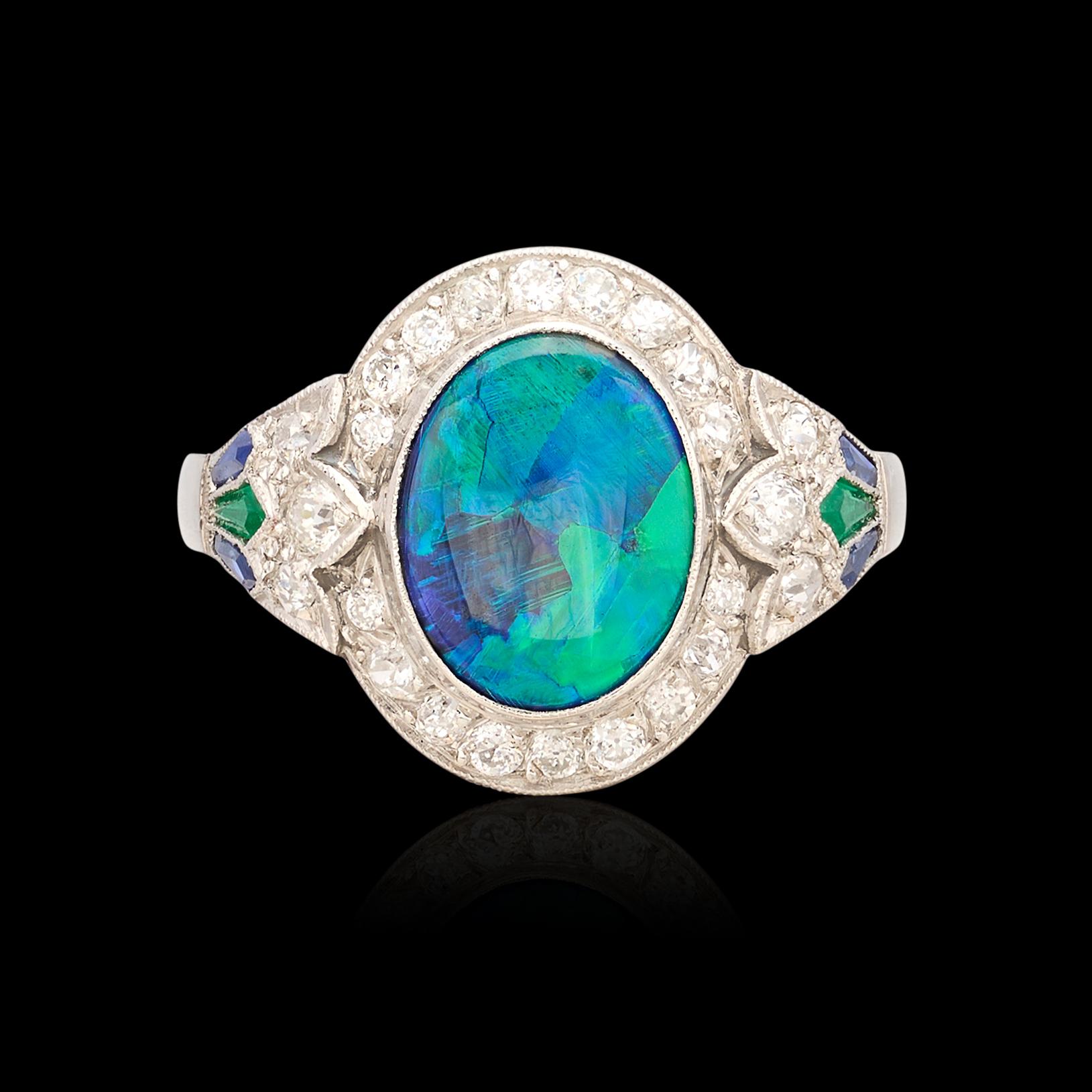 This Art Deco style ring brings the color! The platinum ring centers an oval-shaped black opal, with beautiful deep plays of blue and green, weighing 1.93 carats and measuring 10.0 x 8.0mm, framed with European and old single-cut diamonds weighing