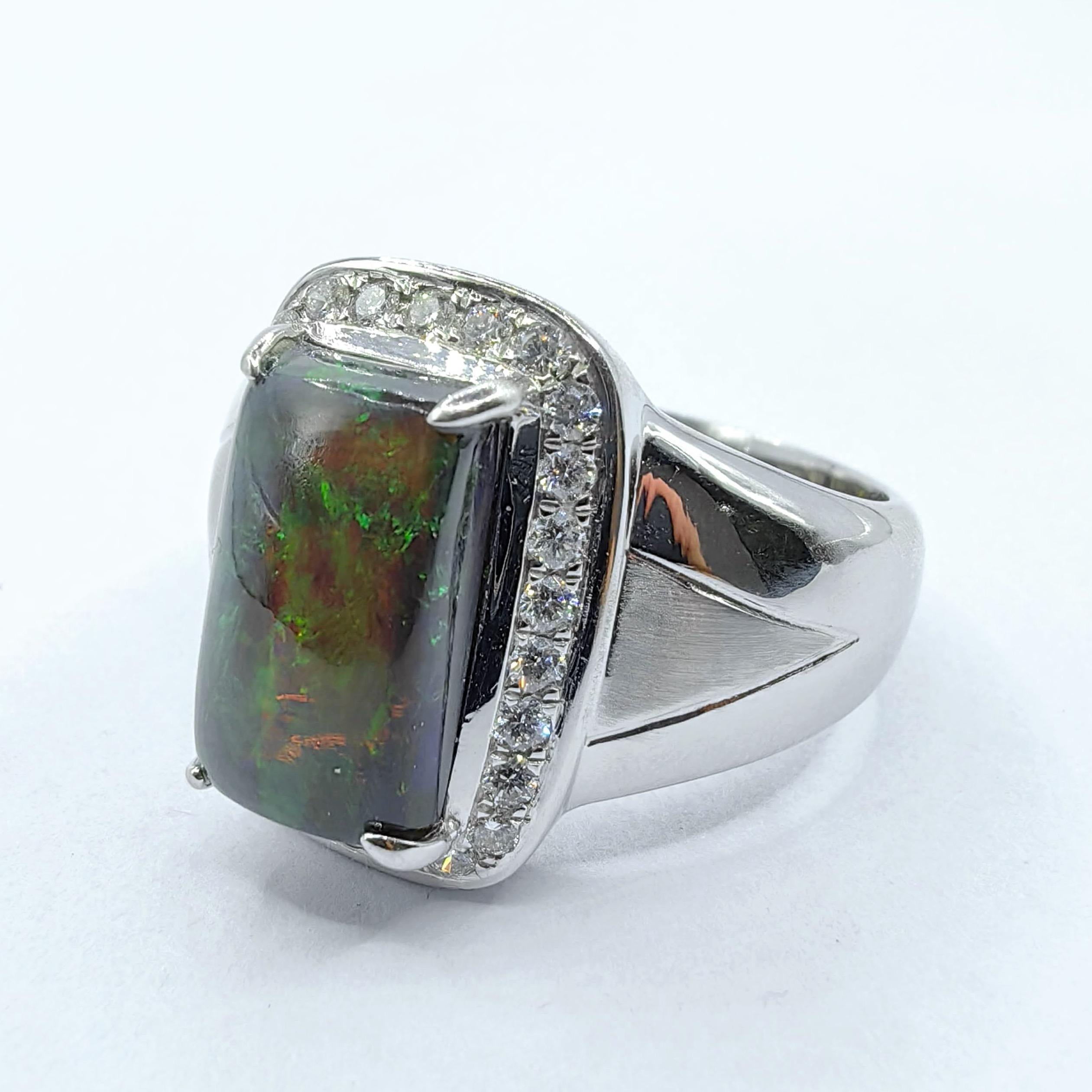 Eleva la tua collezione di gioielli con questo anello mozzafiato con opale nero cabochon e diamanti in oro bianco 18 carati. Al centro di questo audace pezzo forte si trova un opale nero rettangolare tagliato a cabochon, che mostra un ipnotico gioco